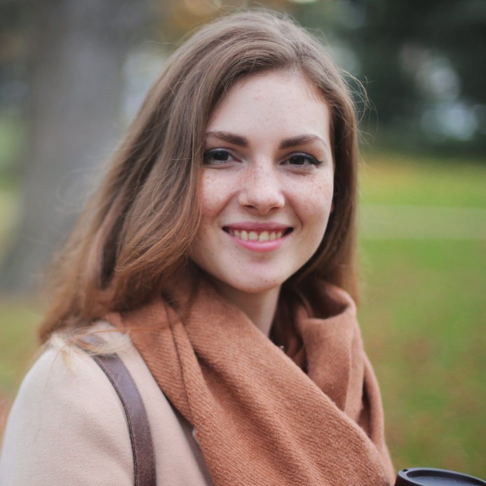 Primo piano del volto di una donna che indossa una sciarpa e un trench.