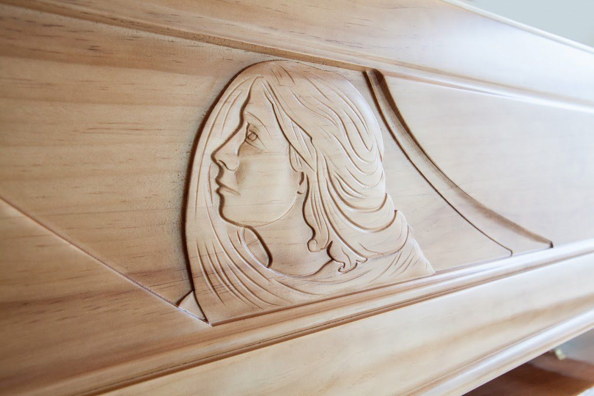 Scultura in legno raffigurante un profilo di donna, con capelli fluenti, inserita in una cornice geometrica in stile Art Déco.