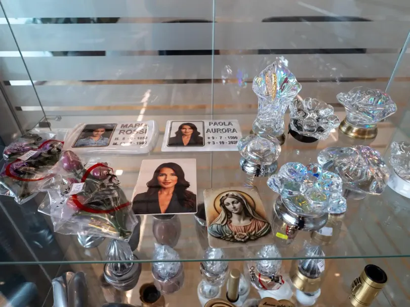 Vetrina con ritratti commemorativi e oggetti decorativi in ​​cristallo.