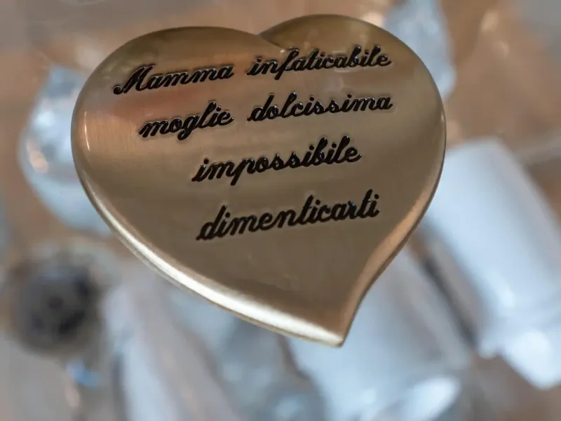 Oggetto d'oro a forma di cuore con inciso il testo italiano: 