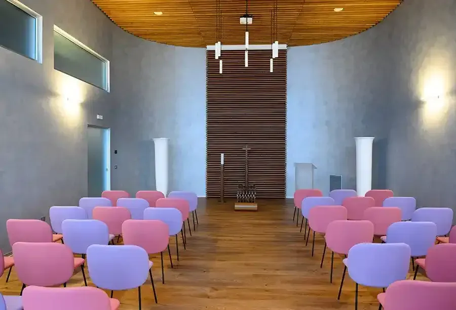 Urna in legno con decorazioni vegetali, casco da motociclista e bare esposte in un negozio ben illuminato.