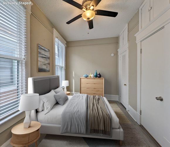 Bedroom with bed, dresser, built-in wardrobe, windows with blinds, and ceiling fan.