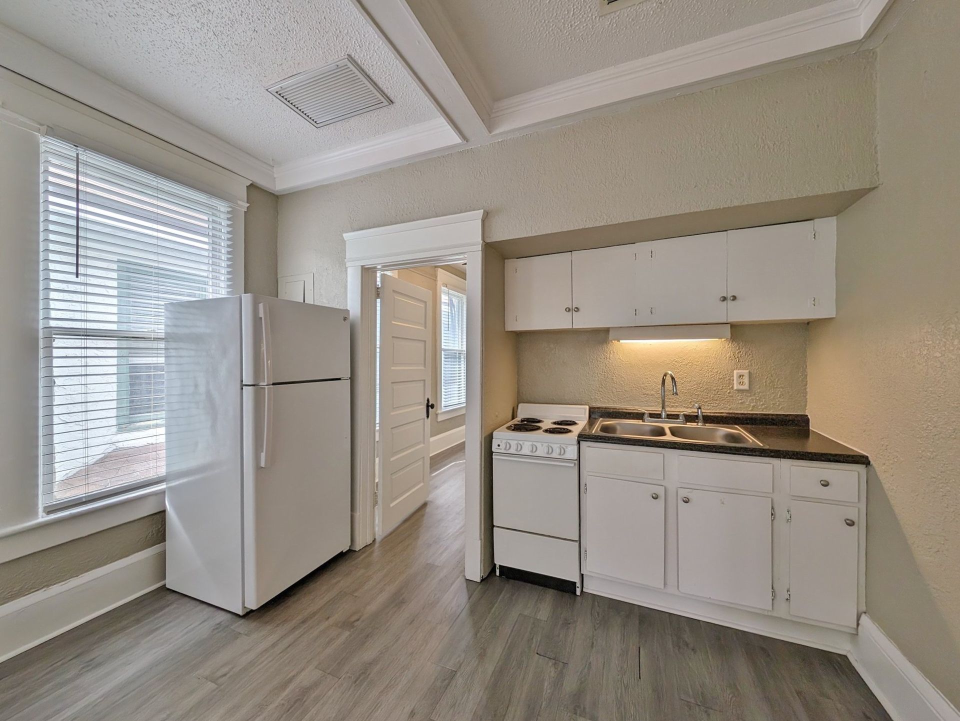 Small kitchen with white appliances, cabinets, and a doorway.