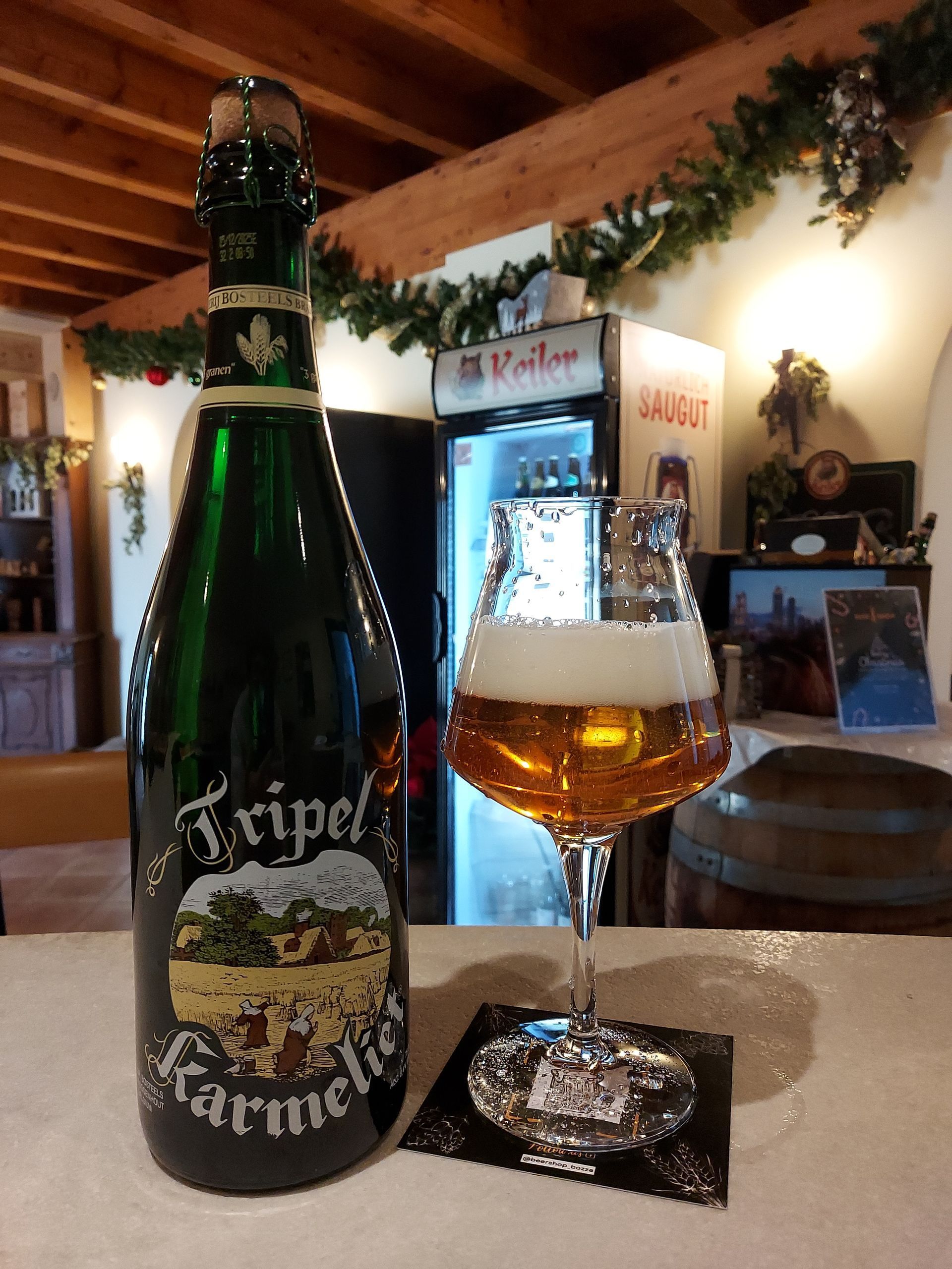 Una bottiglia di tripel è accanto a un bicchiere di birra su un tavolo.
