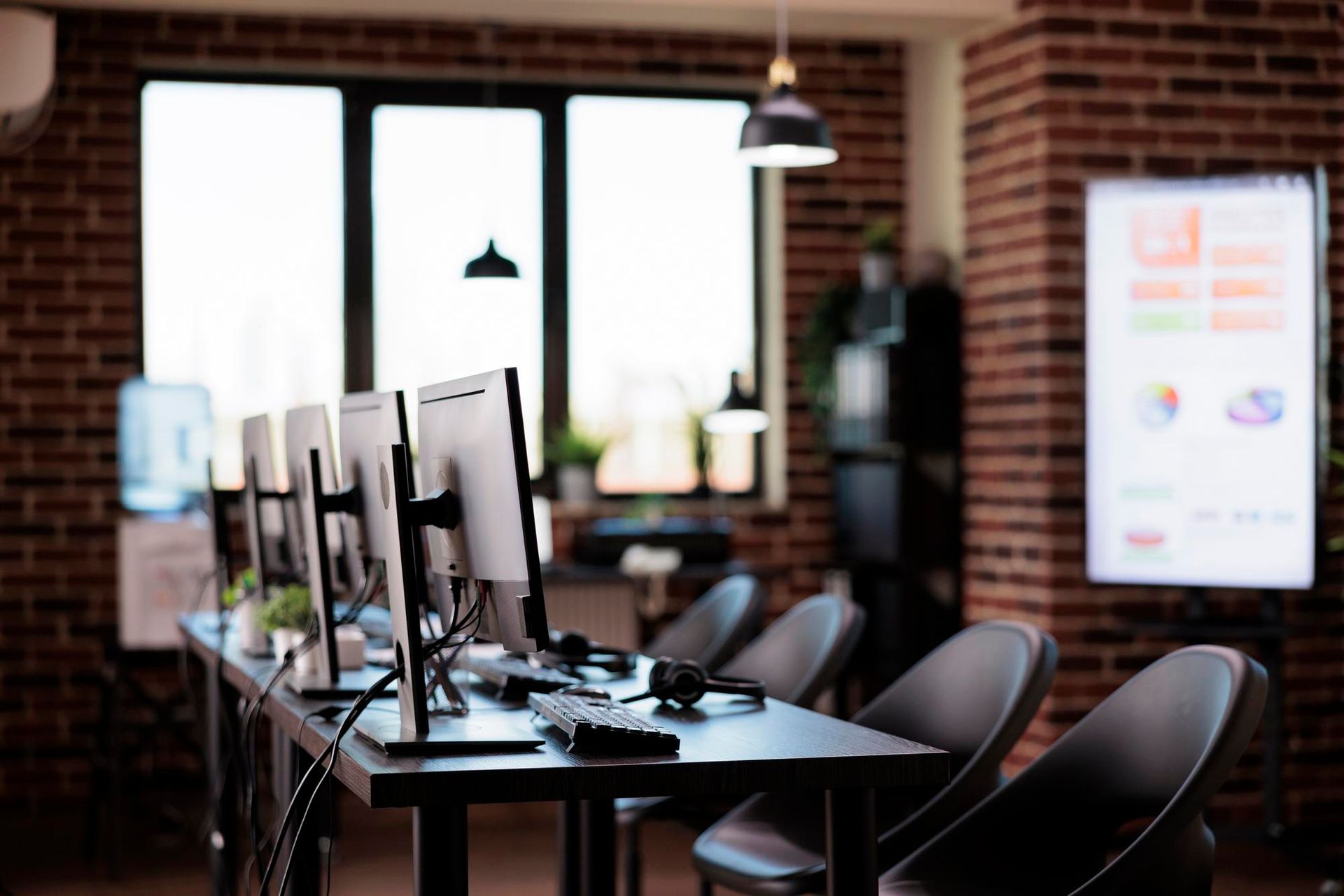 A row of computer monitors are sitting on a table in an office.