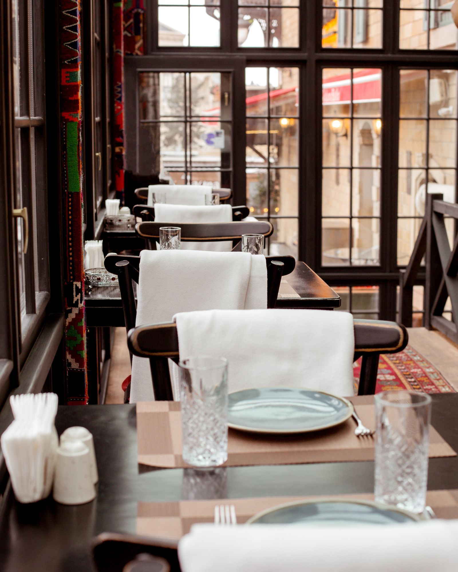 A restaurant filled with tables and chairs with plates and glasses on them.