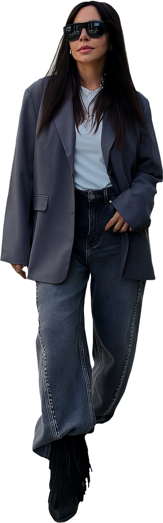 Donna con occhiali da sole e blazer oversize, top azzurro, jeans scuri e stivali.