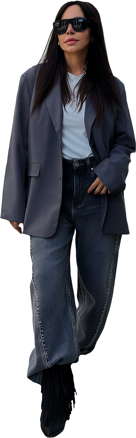 Donna con occhiali da sole e blazer oversize, top azzurro, jeans scuri e stivali.