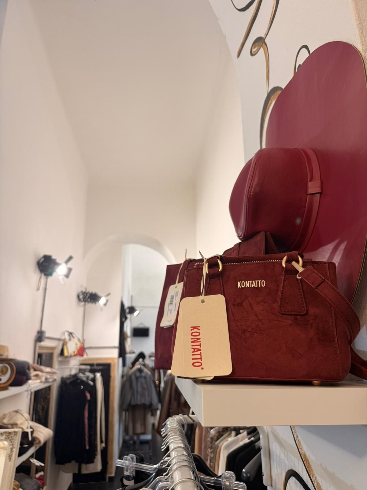 Borsa marrone con etichetta in un negozio di abbigliamento, con un cappello rosso dietro.