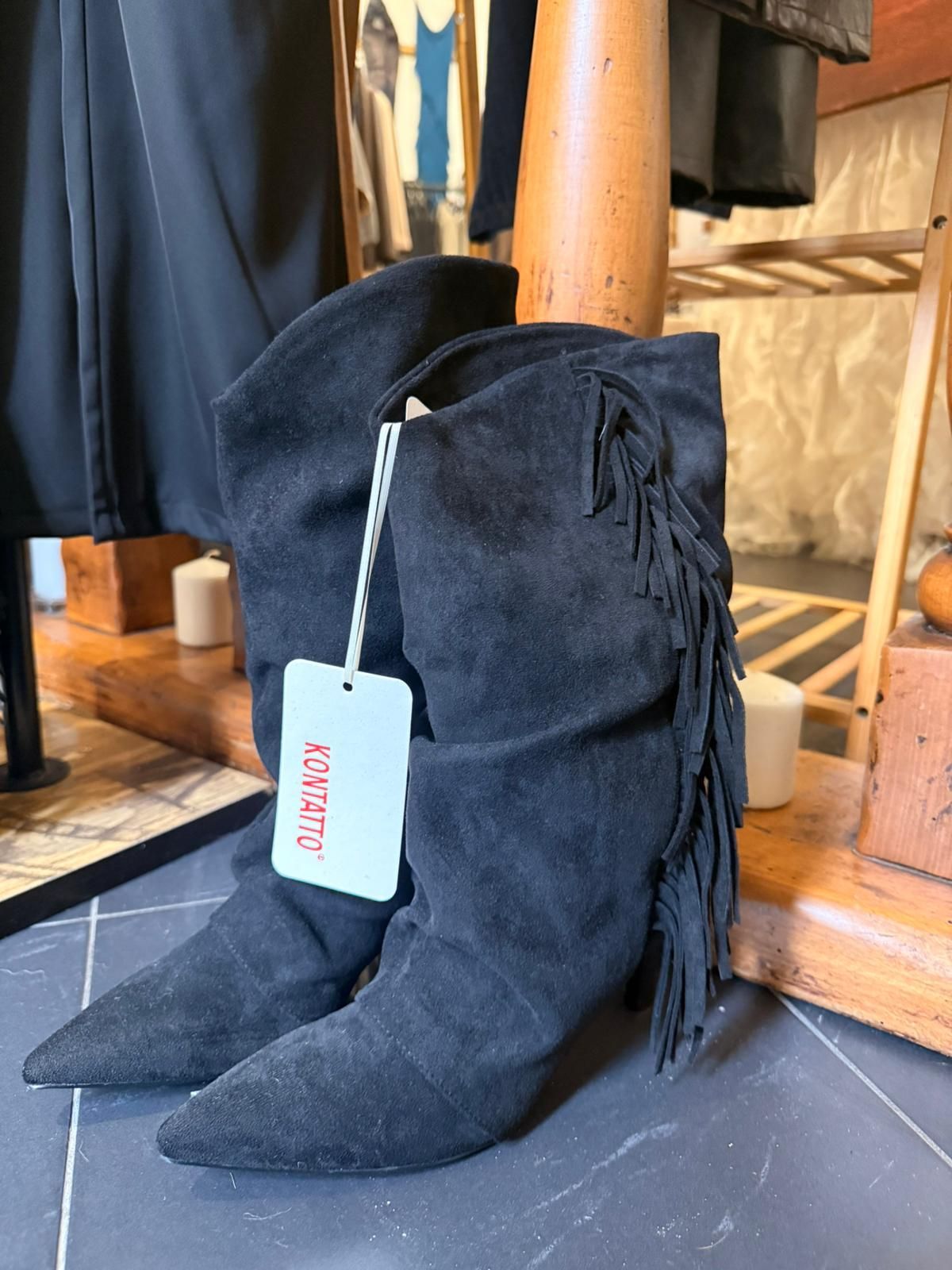 Stivali neri in pelle scamosciata con frange e etichetta bianca.