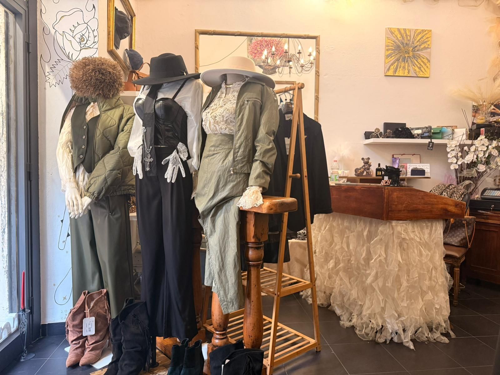 Donna con abito avvolgente in maglia color crema e borsa marrone, accovacciata vicino a un muro di mattoni.