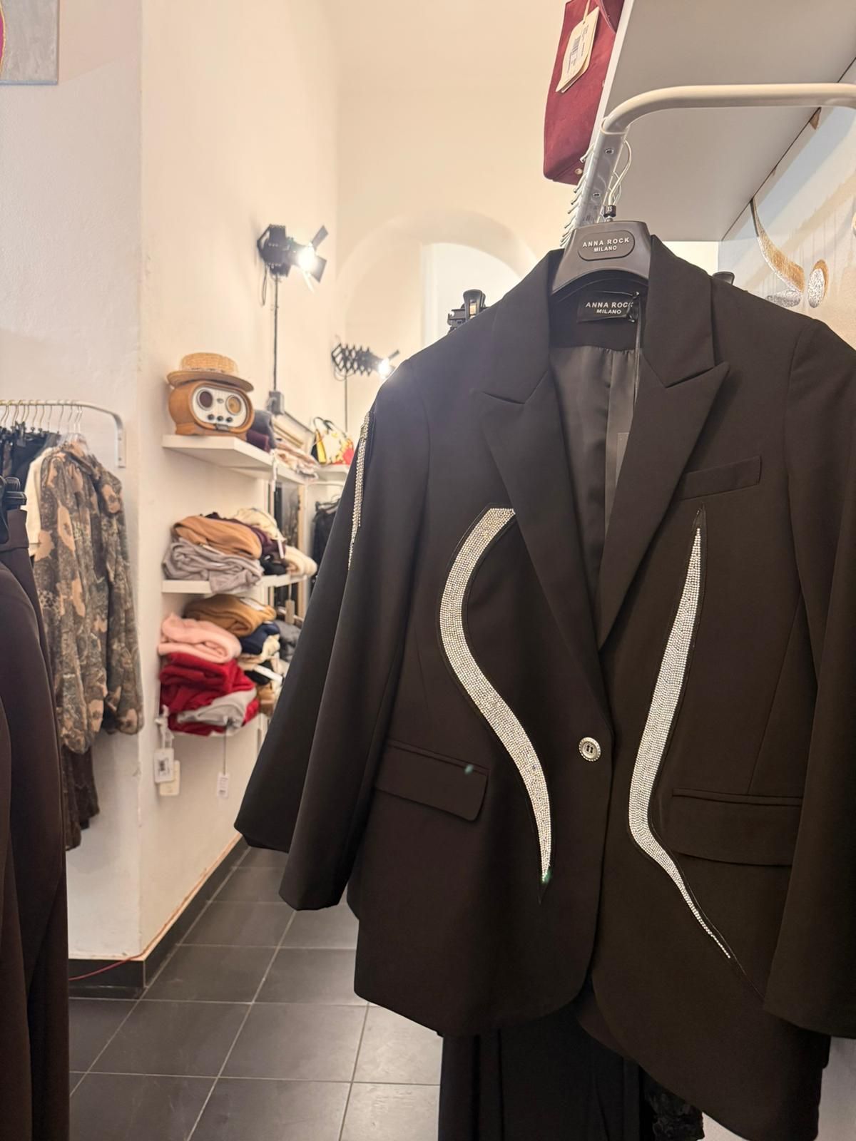 Blazer nero con disegno astratto bianco appeso in un negozio di abbigliamento.