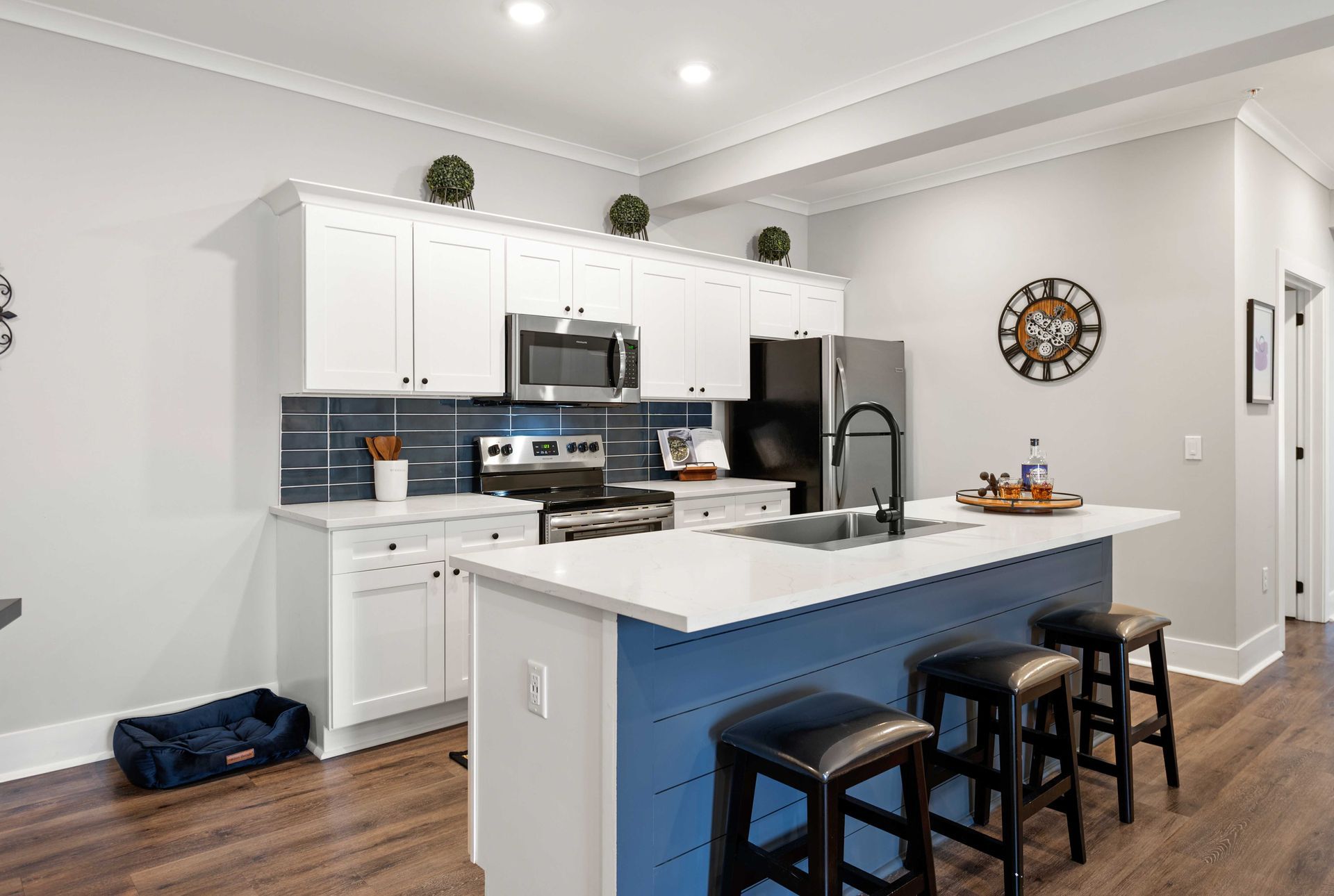 Apartment kitchen with white cabinets, stainless steel appliances, and a blue island.