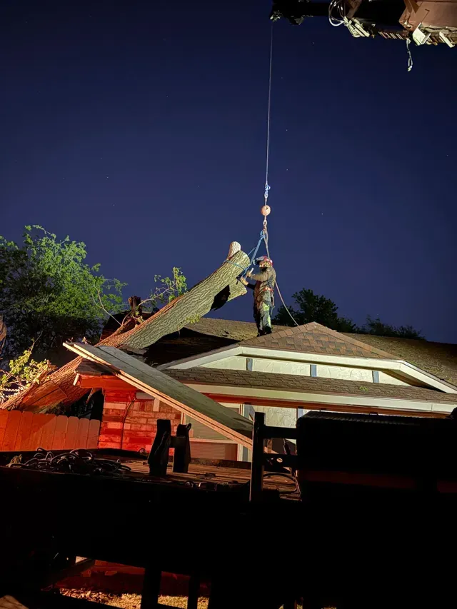 Worker hoisting a roof beam at night on a house under construction