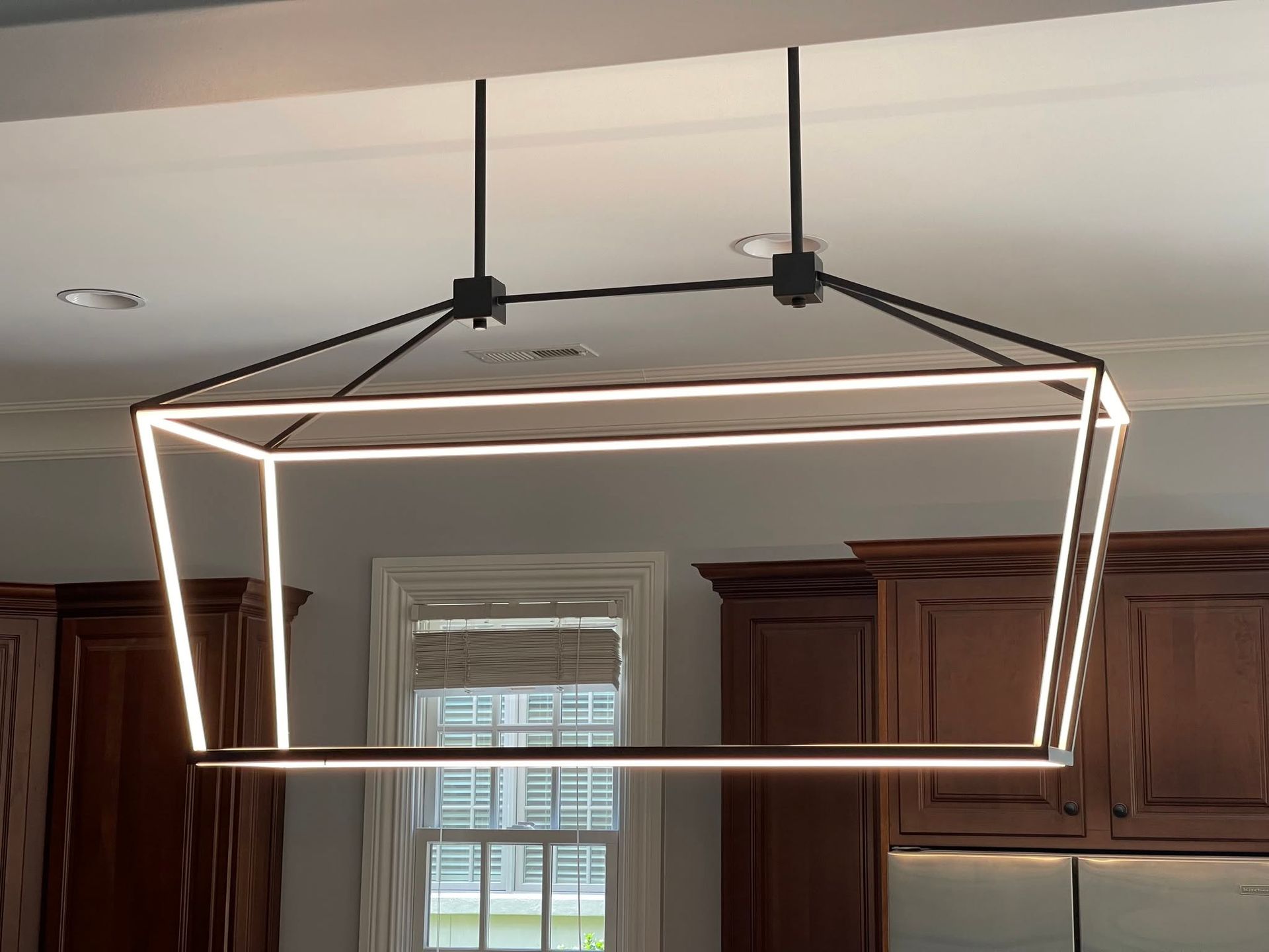 Modern rectangular black pendant light above a kitchen cabinet area