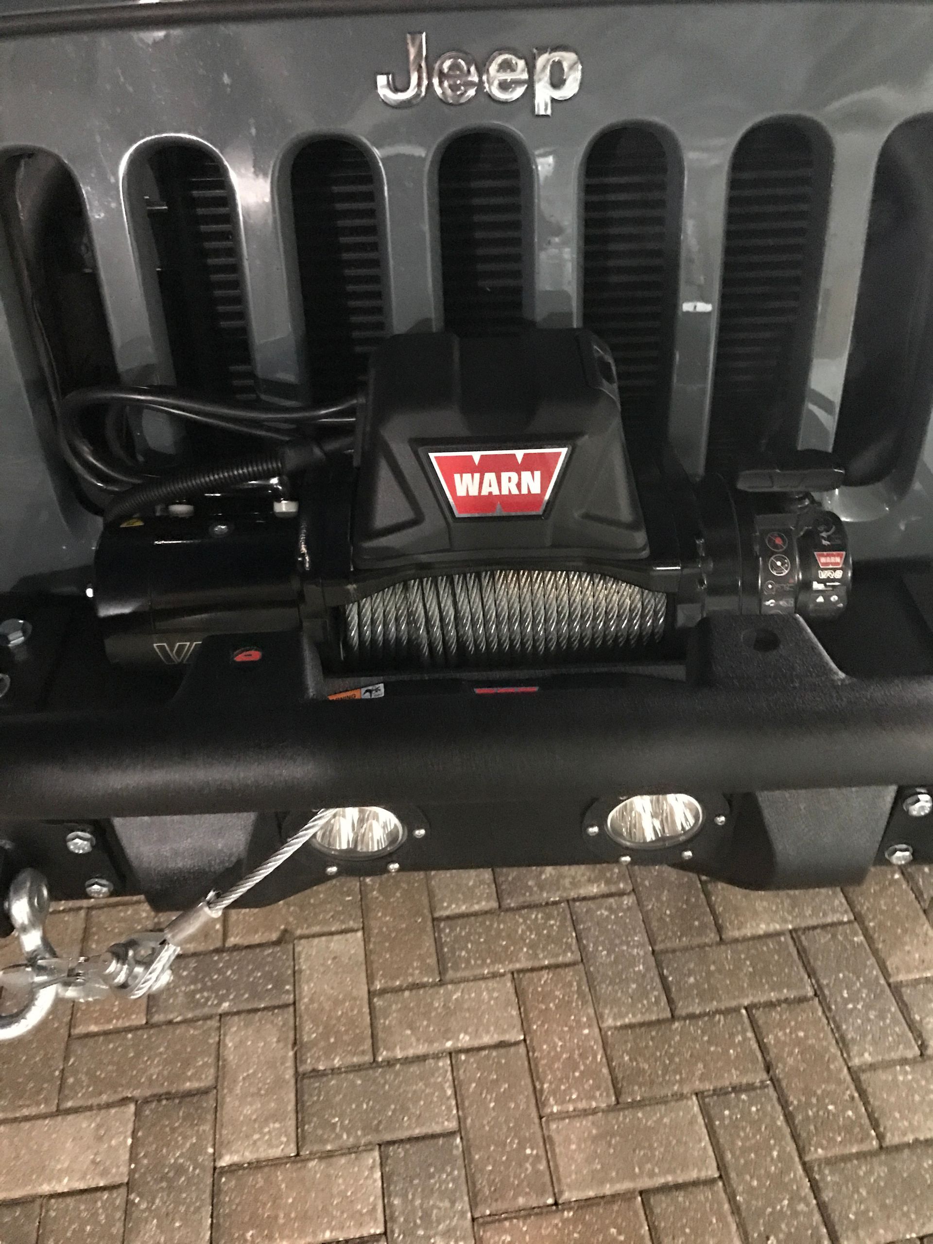 A Jeep With a Winch Attached to the Front Bumper is Parked on a Brick Driveway - Mr. Best Wrench