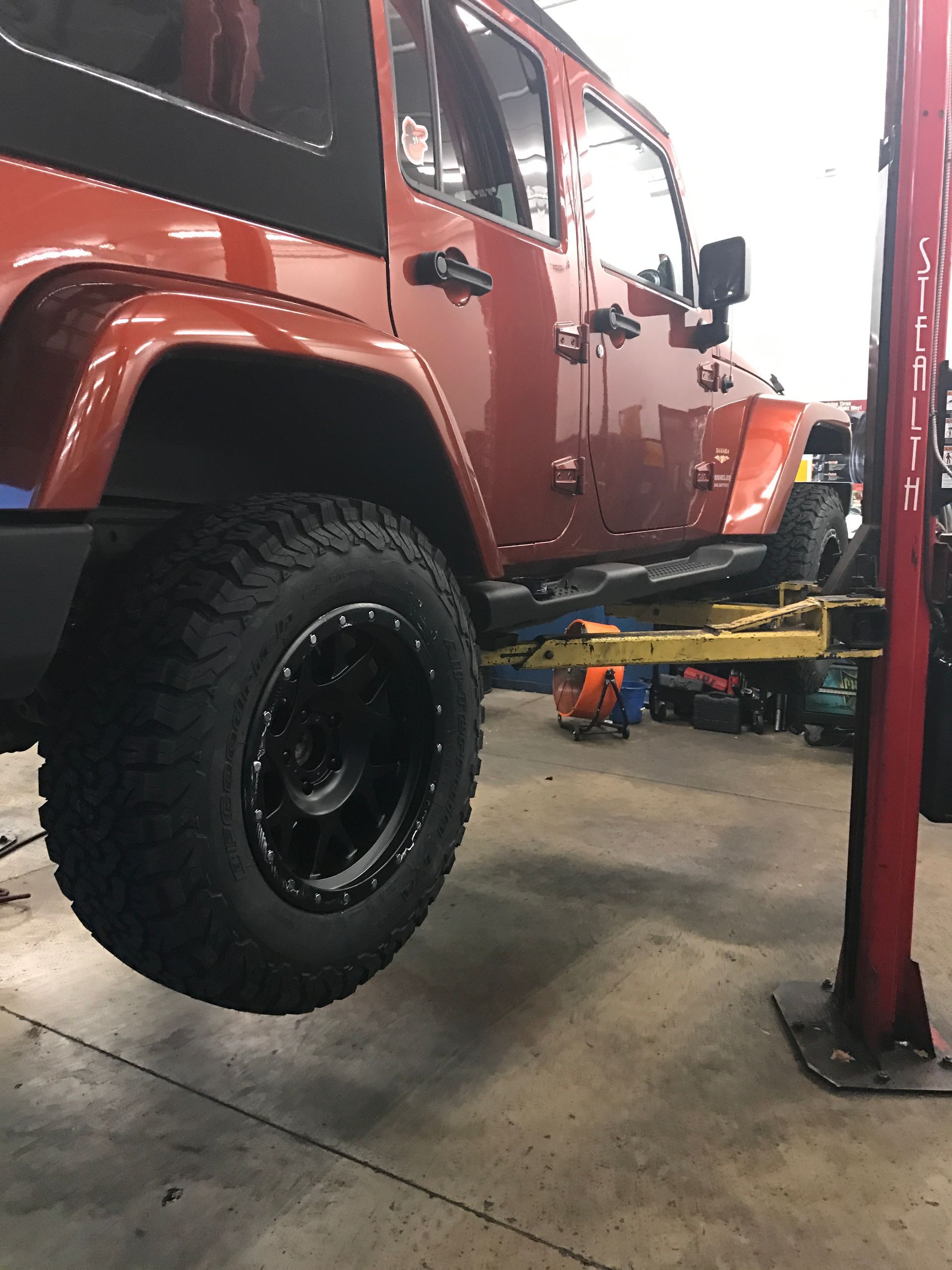 A Red Jeep is on a Lift in Our Auto Repair Shop in Jacksonville, FL - Mr. Best Wrench