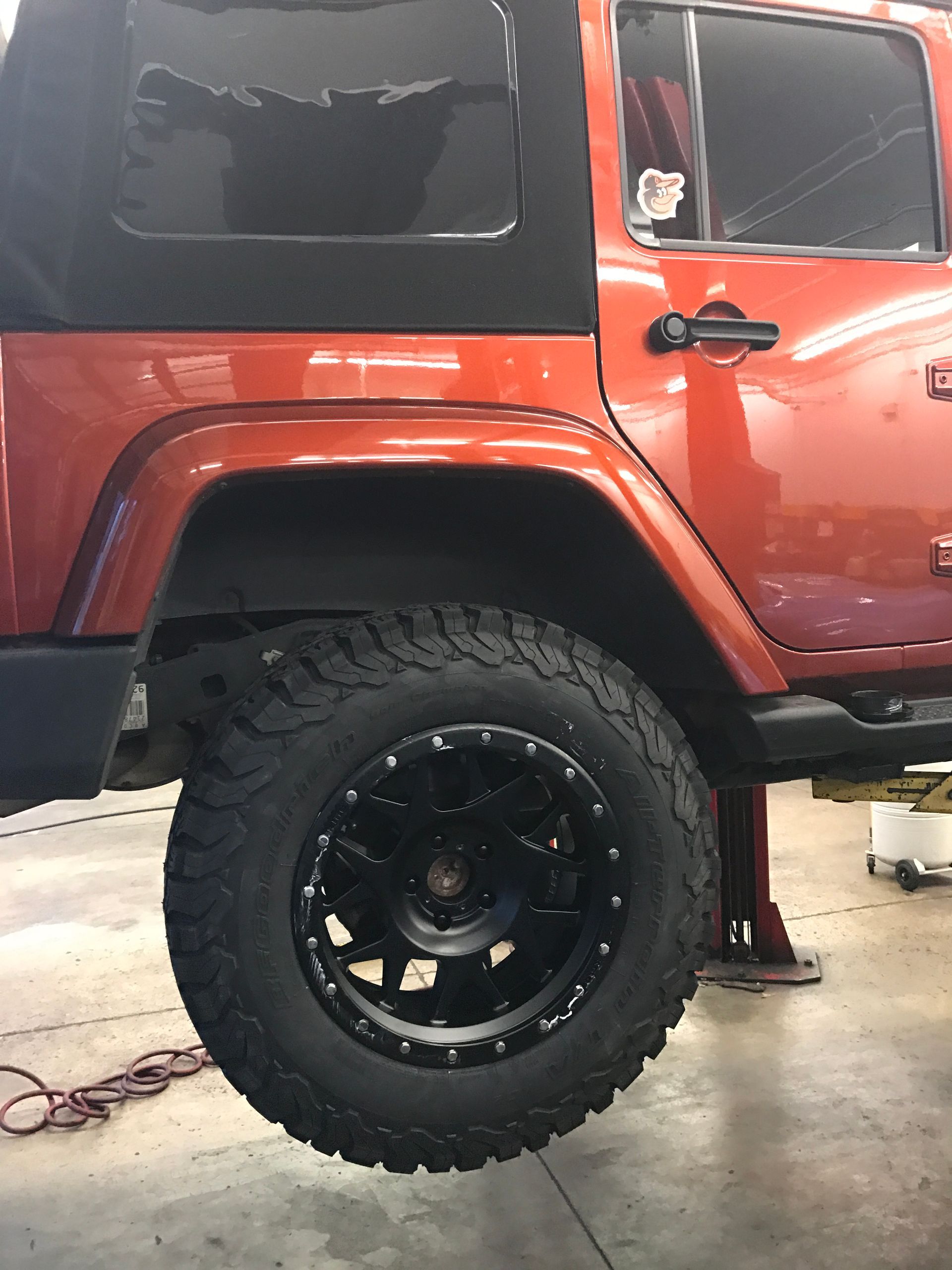 A Red Jeep With Black Wheel on a Lift in Our Garage - Mr. Best Wrench