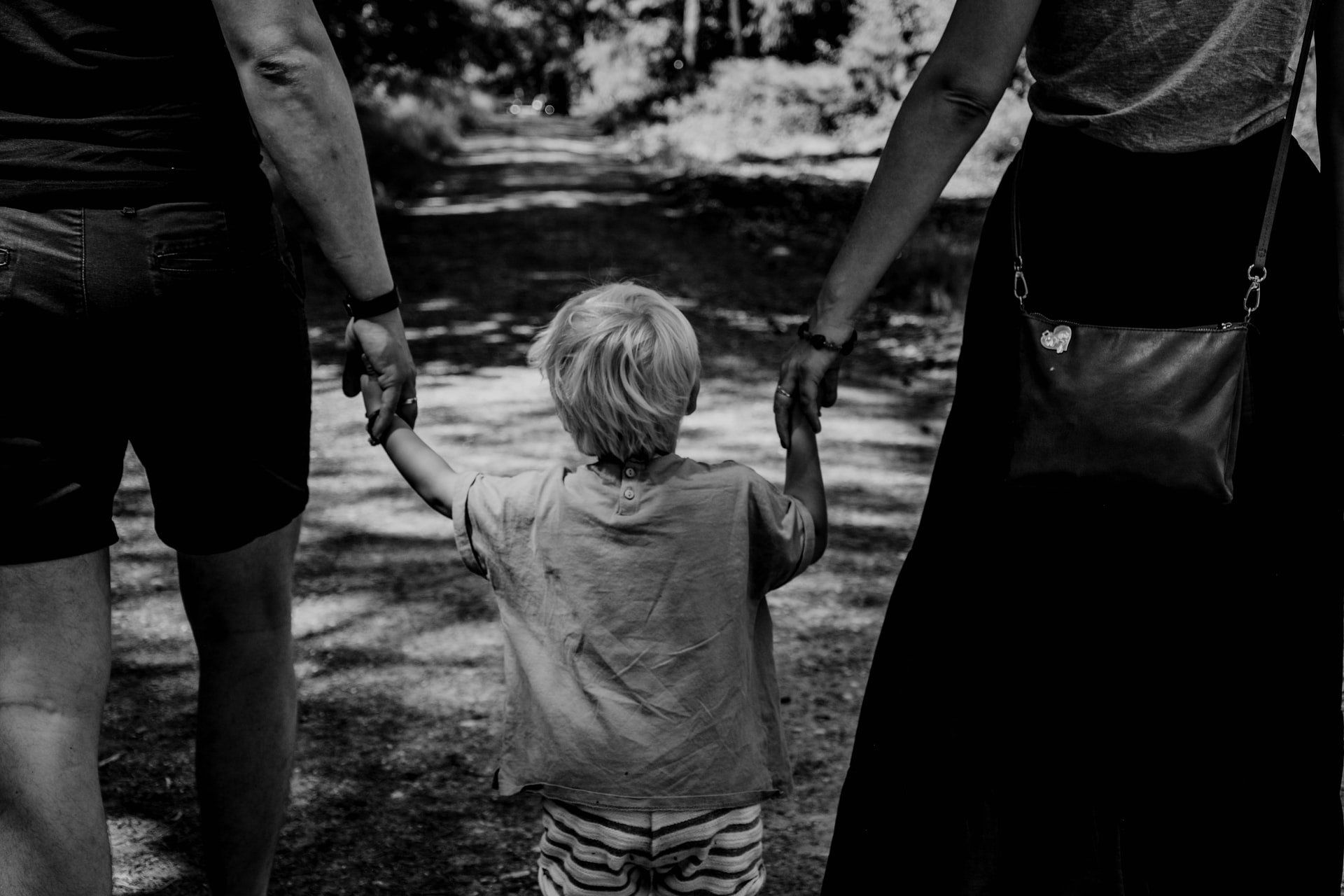 ילד מחזיק בידיים של אמא ואבא