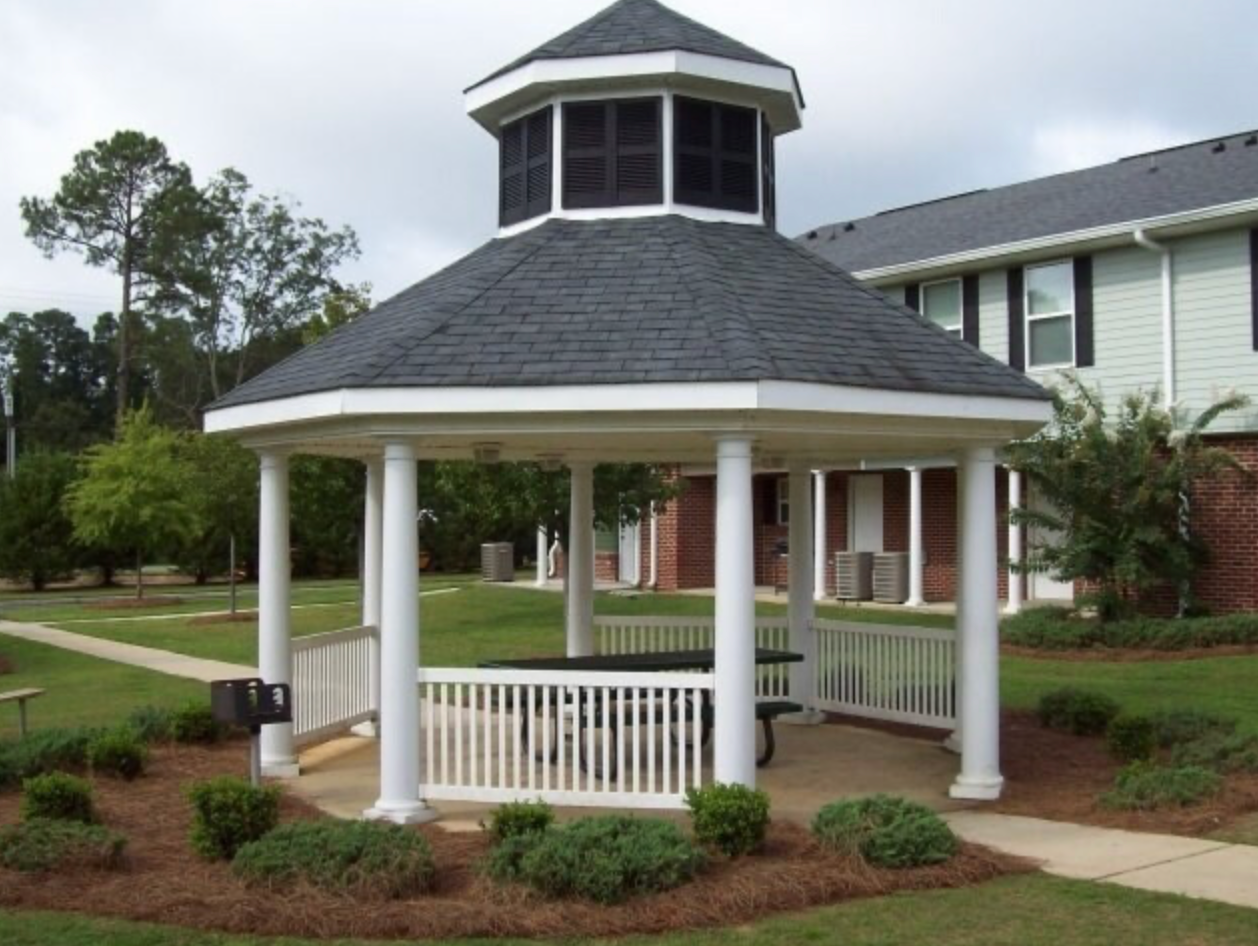 A gazebo with a table and chairs in front of a house
