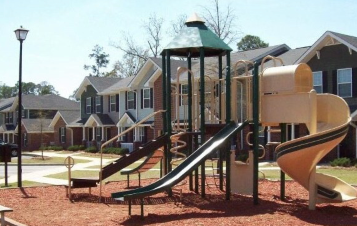 A playground with houses in the background and a slide