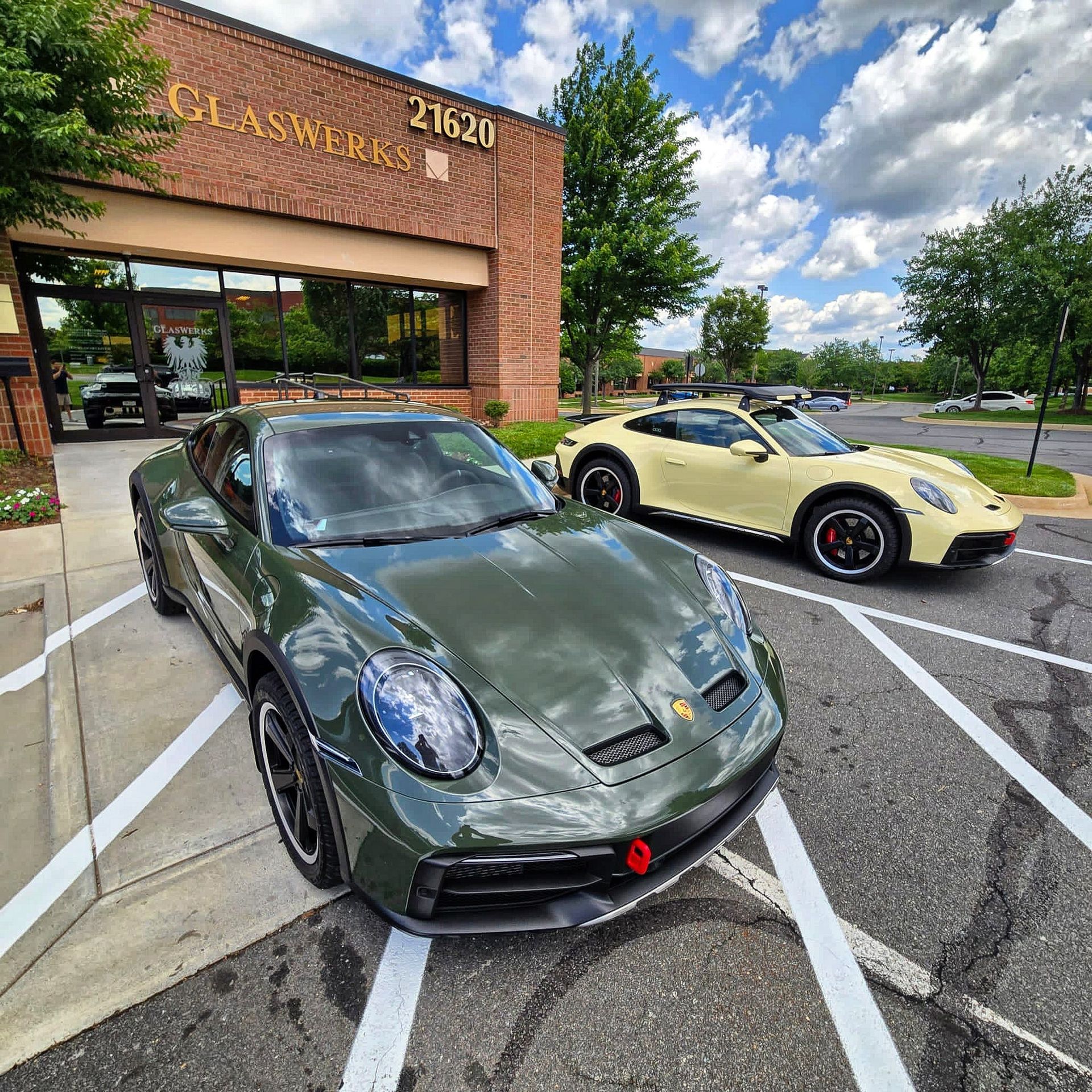 Porsche 911s in green and yellow outside GlasWerks DMV, showcasing PPF protection