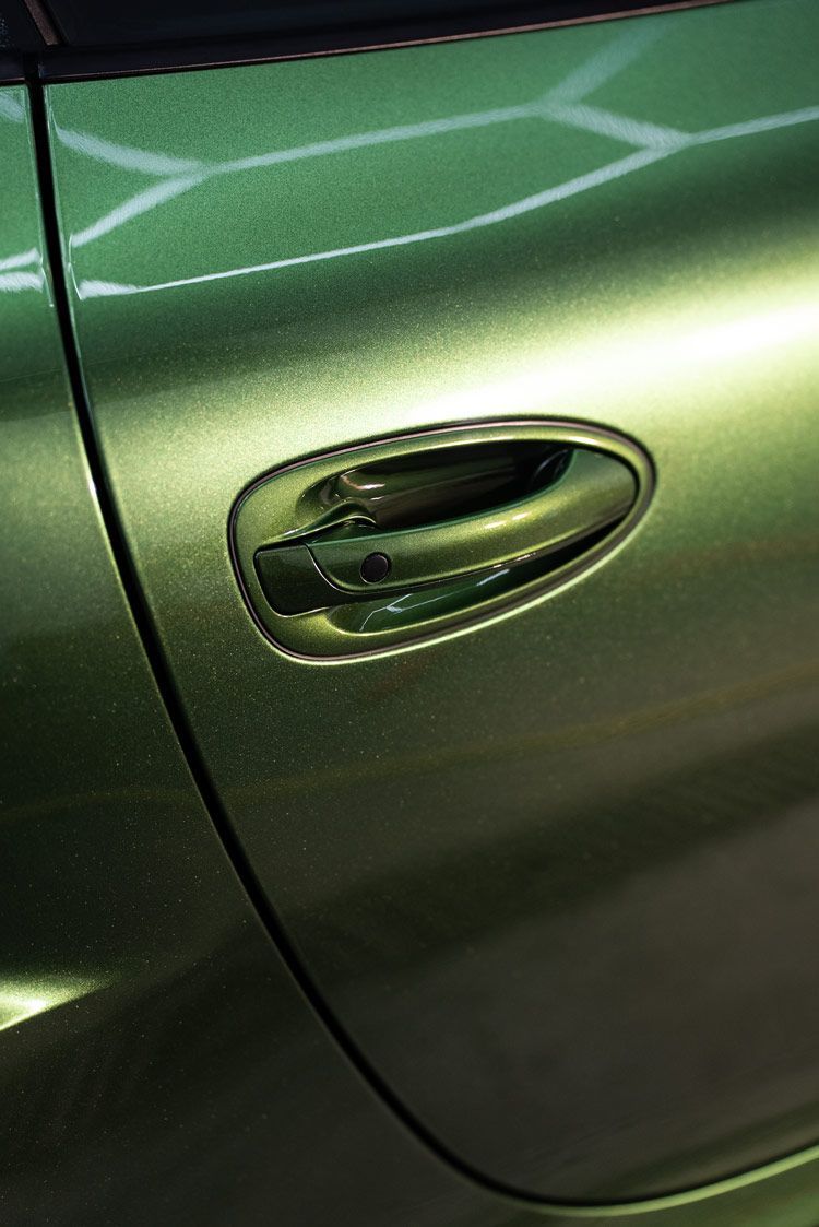 A close up of a green car door handle.
