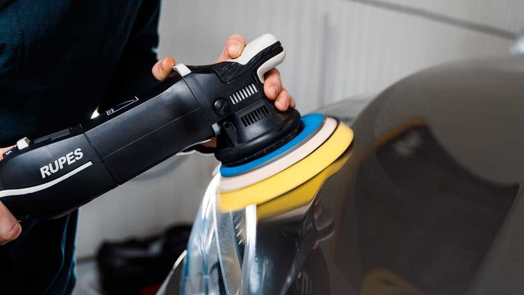 A person is polishing a car with a machine.