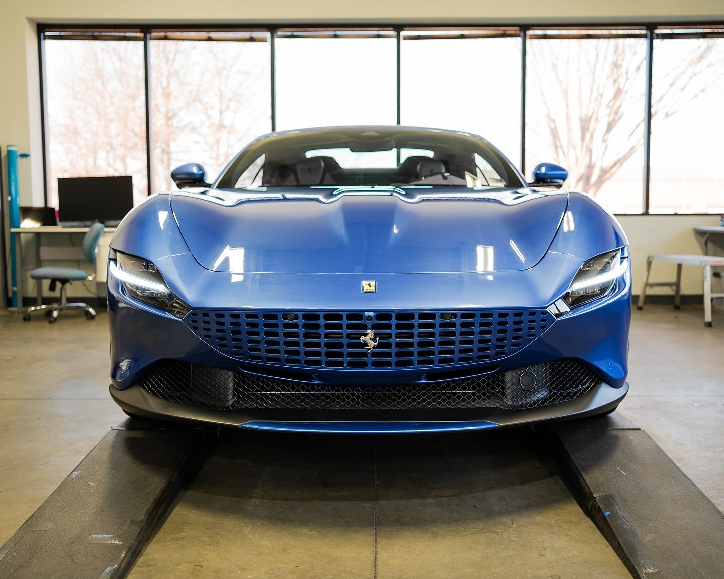 Blue Ferrari sports car with ceramic coating, parked in a detailing shop