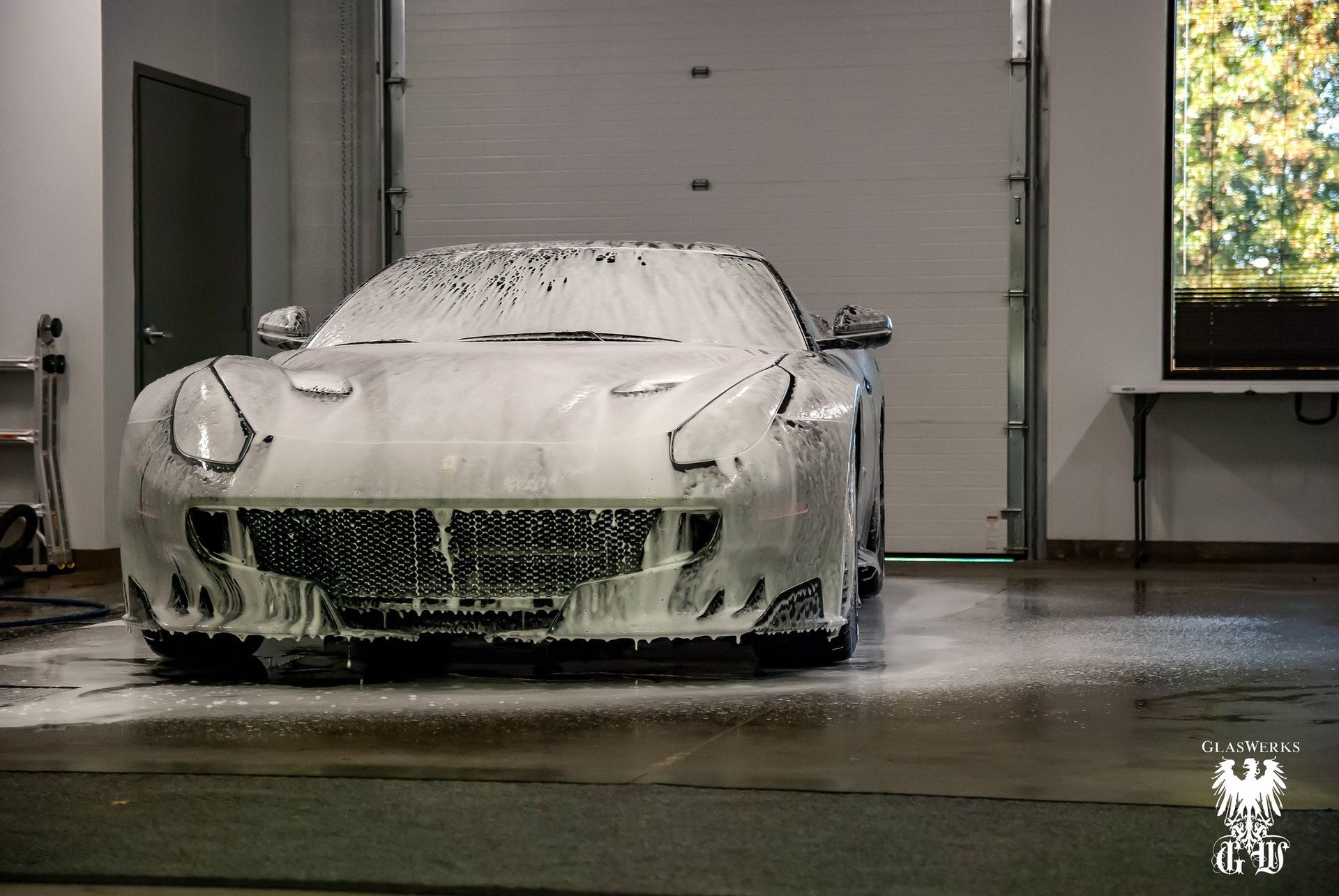 A man is washing a blue sports car in a car wash.