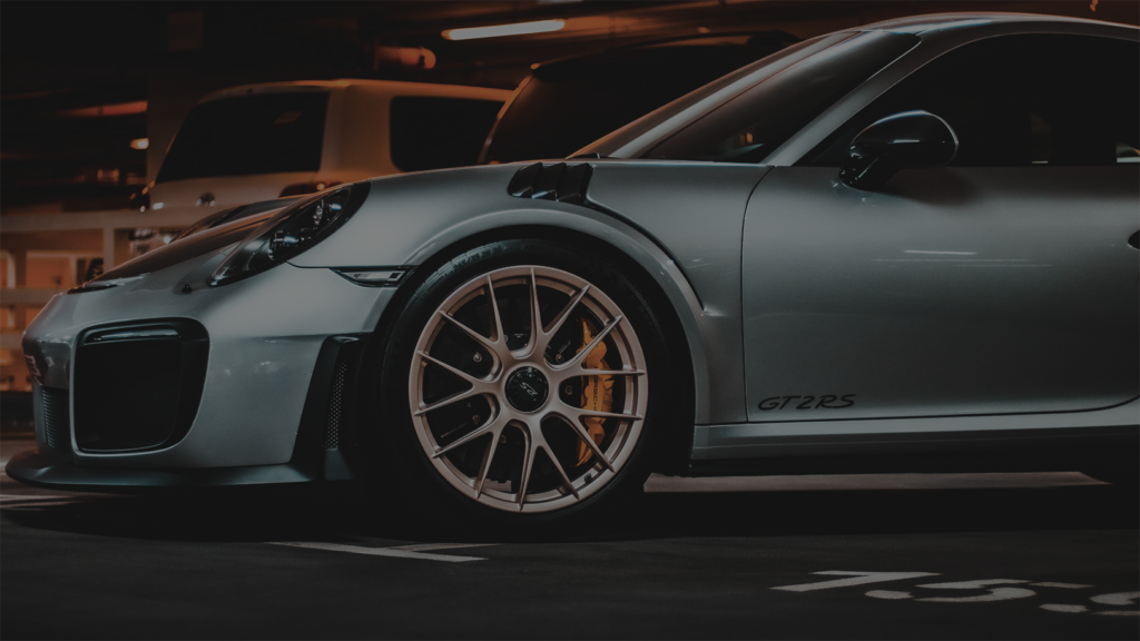 A silver sports car is parked in a parking lot at night.