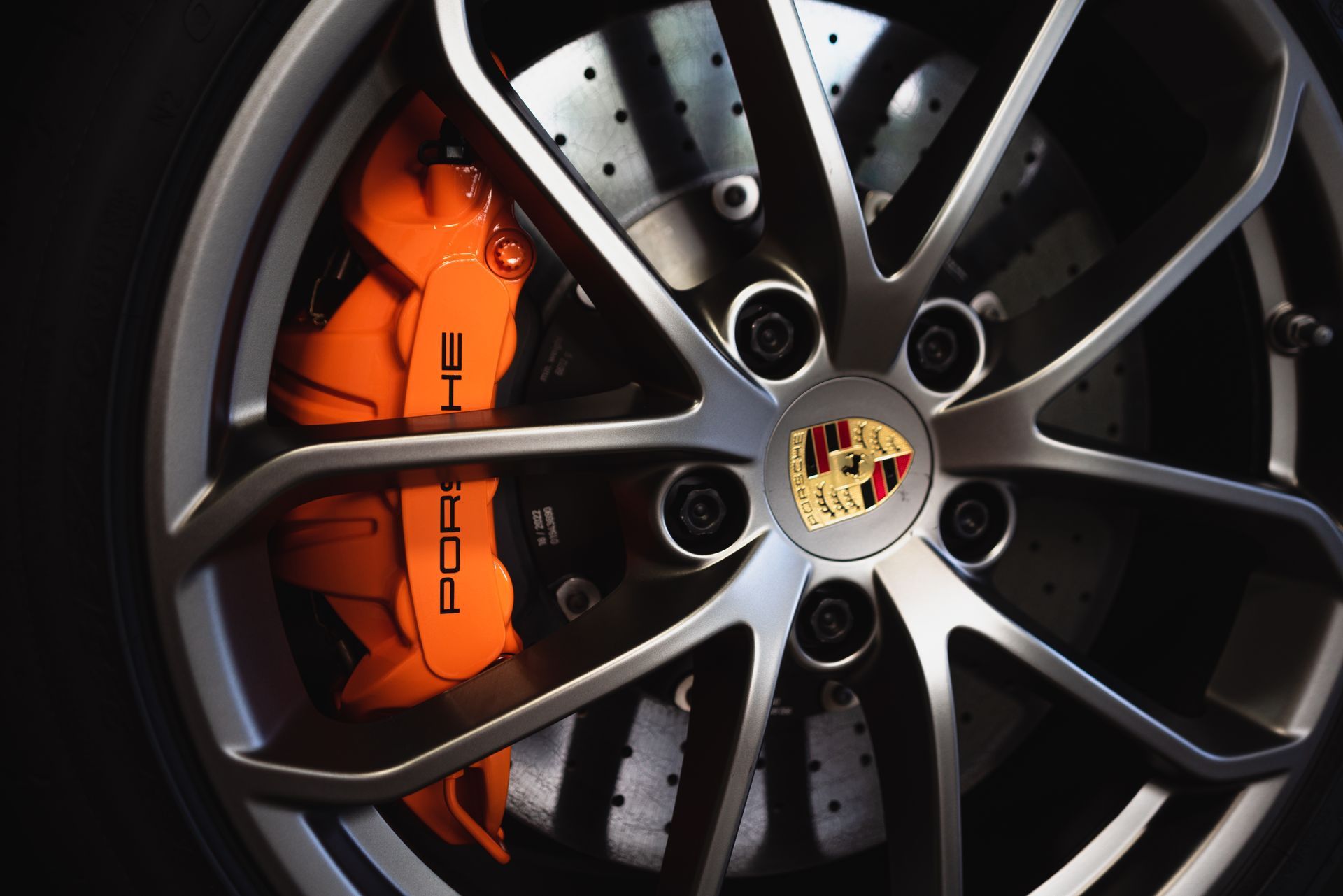 A close up of a porsche wheel with orange brake calipers