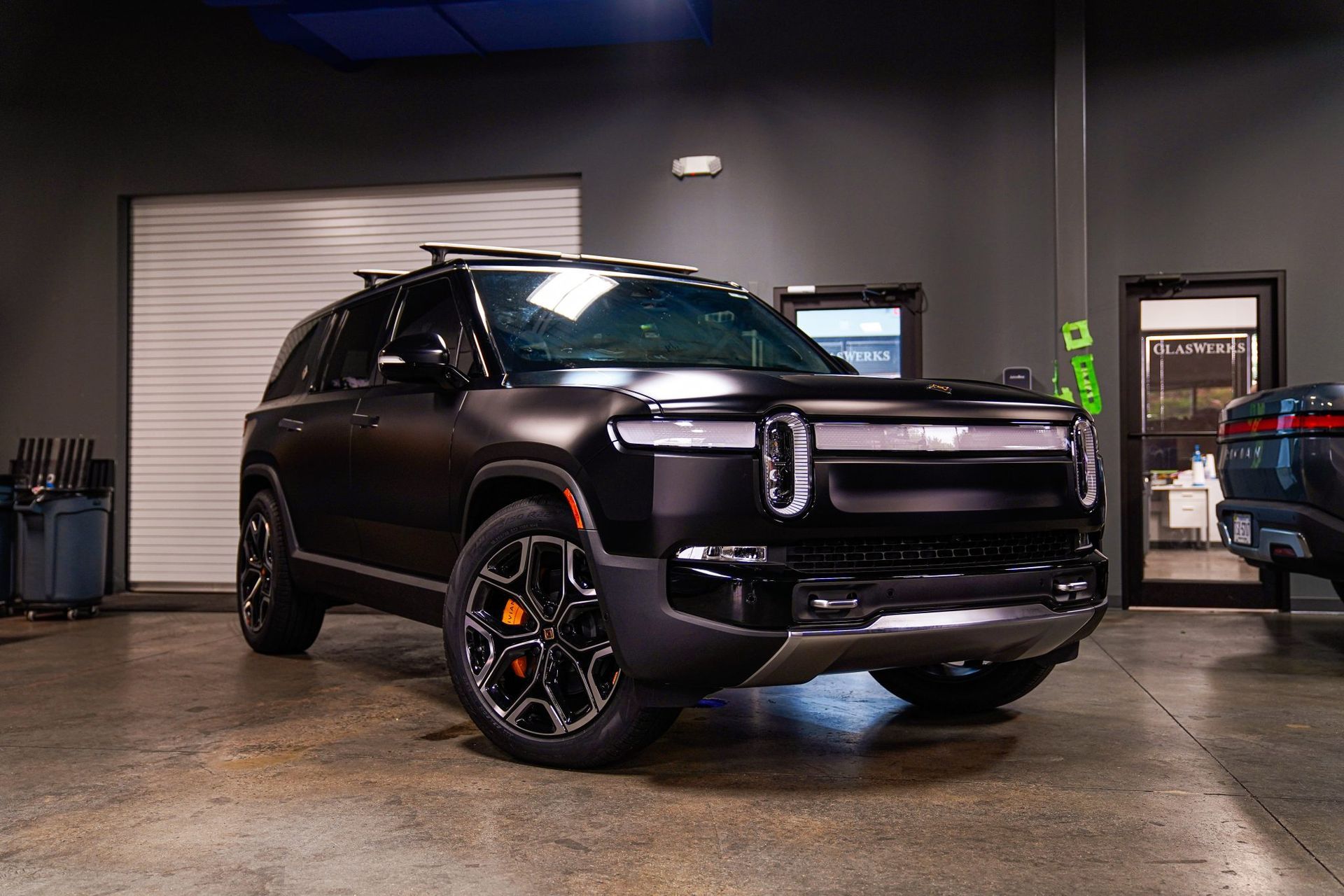 A black suv is parked in a garage next to another car.