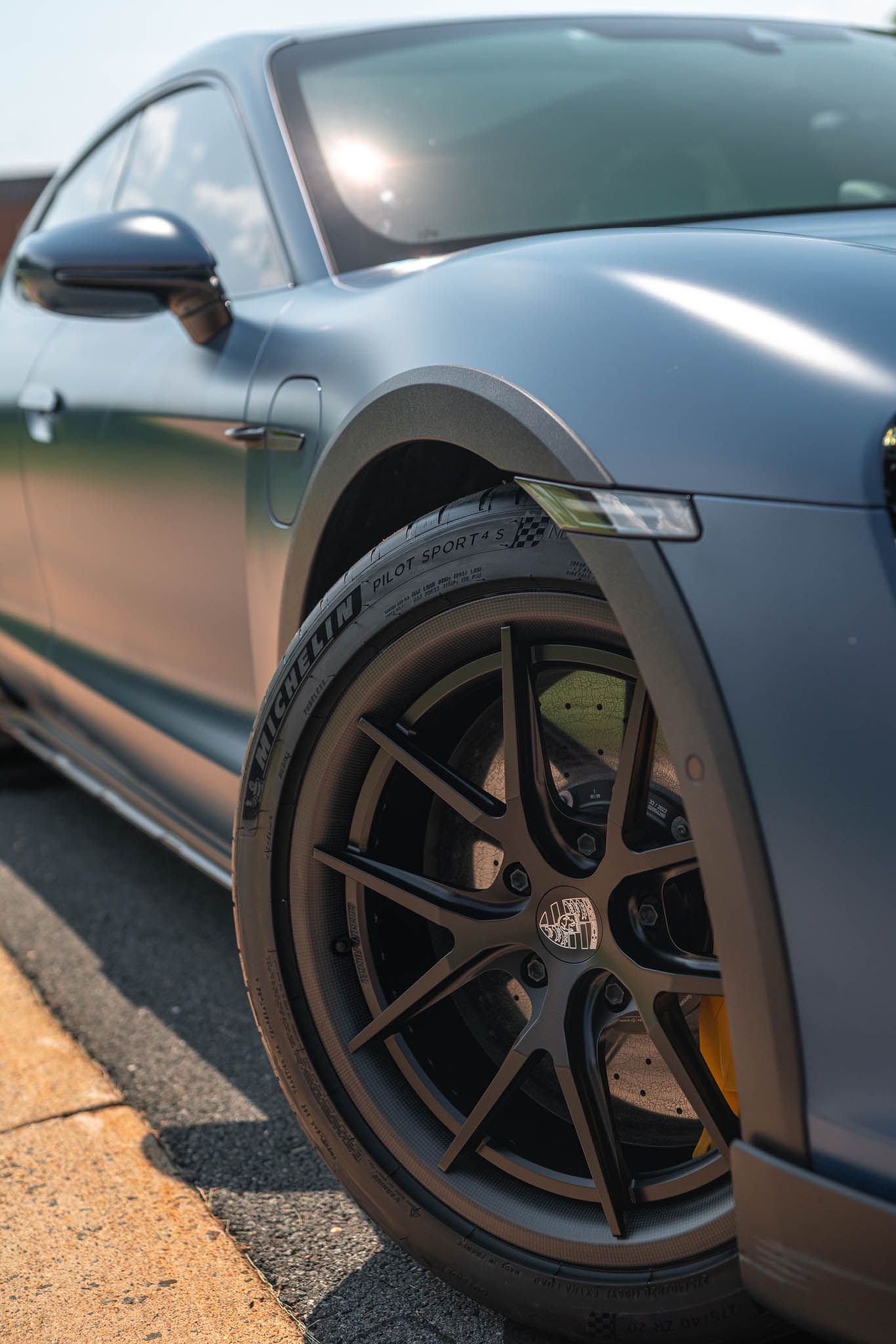 A close up of a porsche taycan turbo s parked on the side of the road.