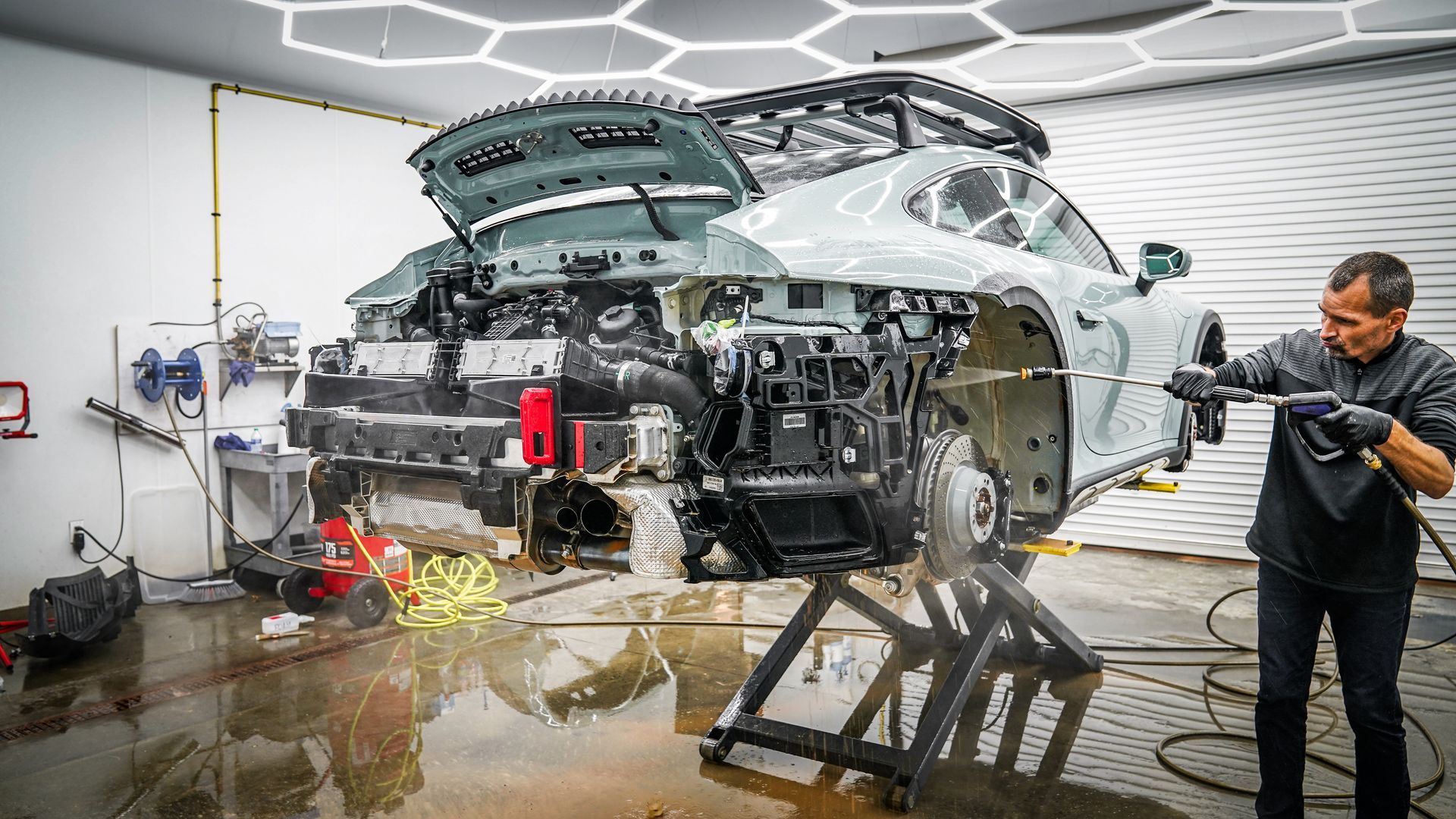 A man is washing a car in a garage.