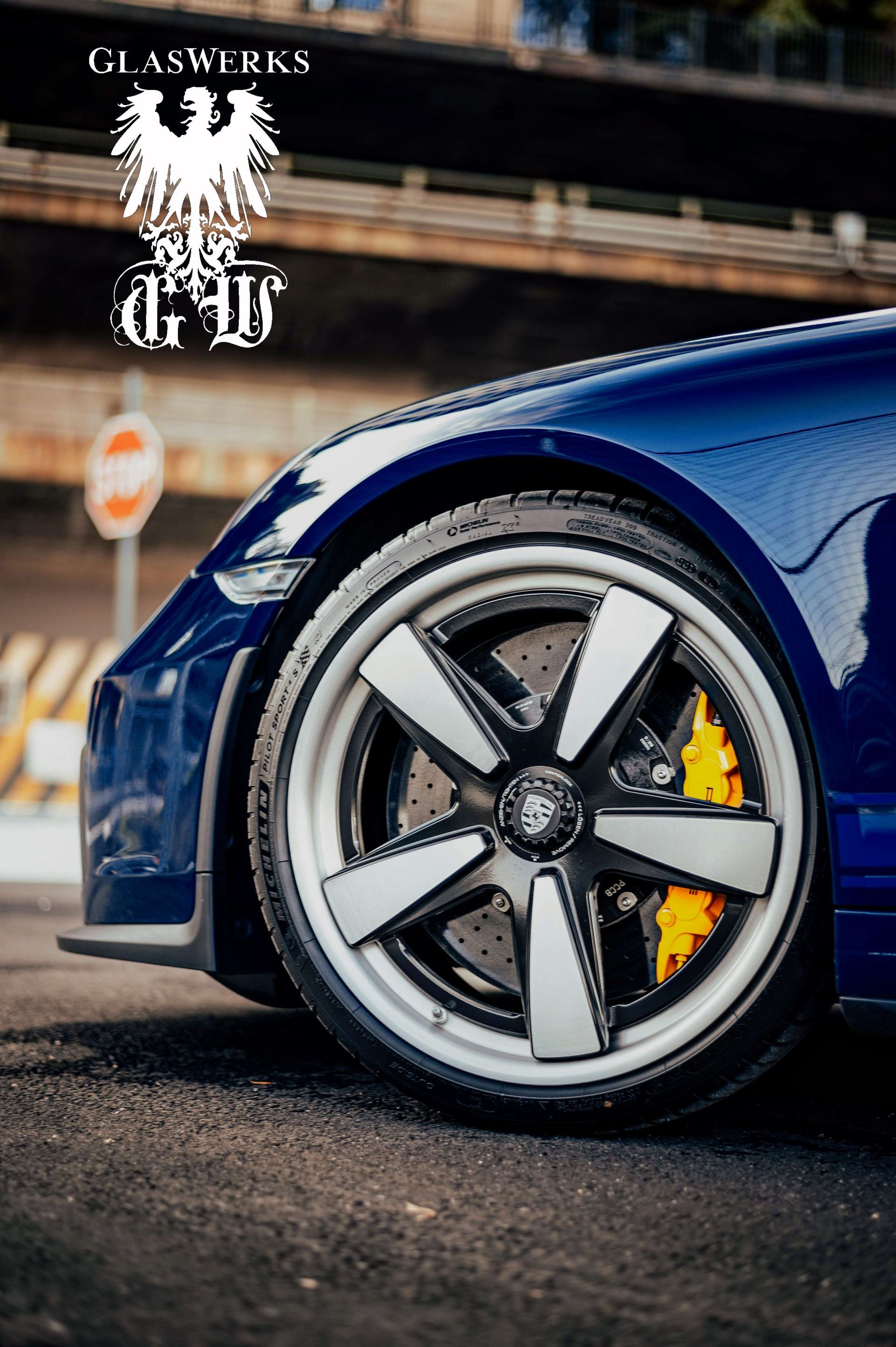 A close up of a blue car with white wheels and brake calipers.