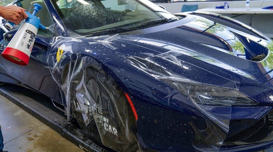 A person is spraying a car with a spray bottle.