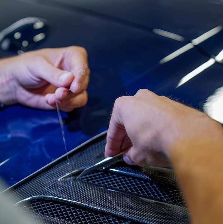 A person is working on the hood of a car