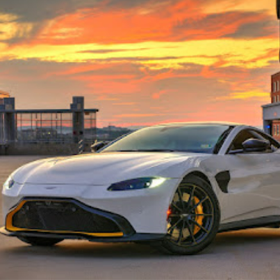 A white sports car is parked in front of a building at sunset.