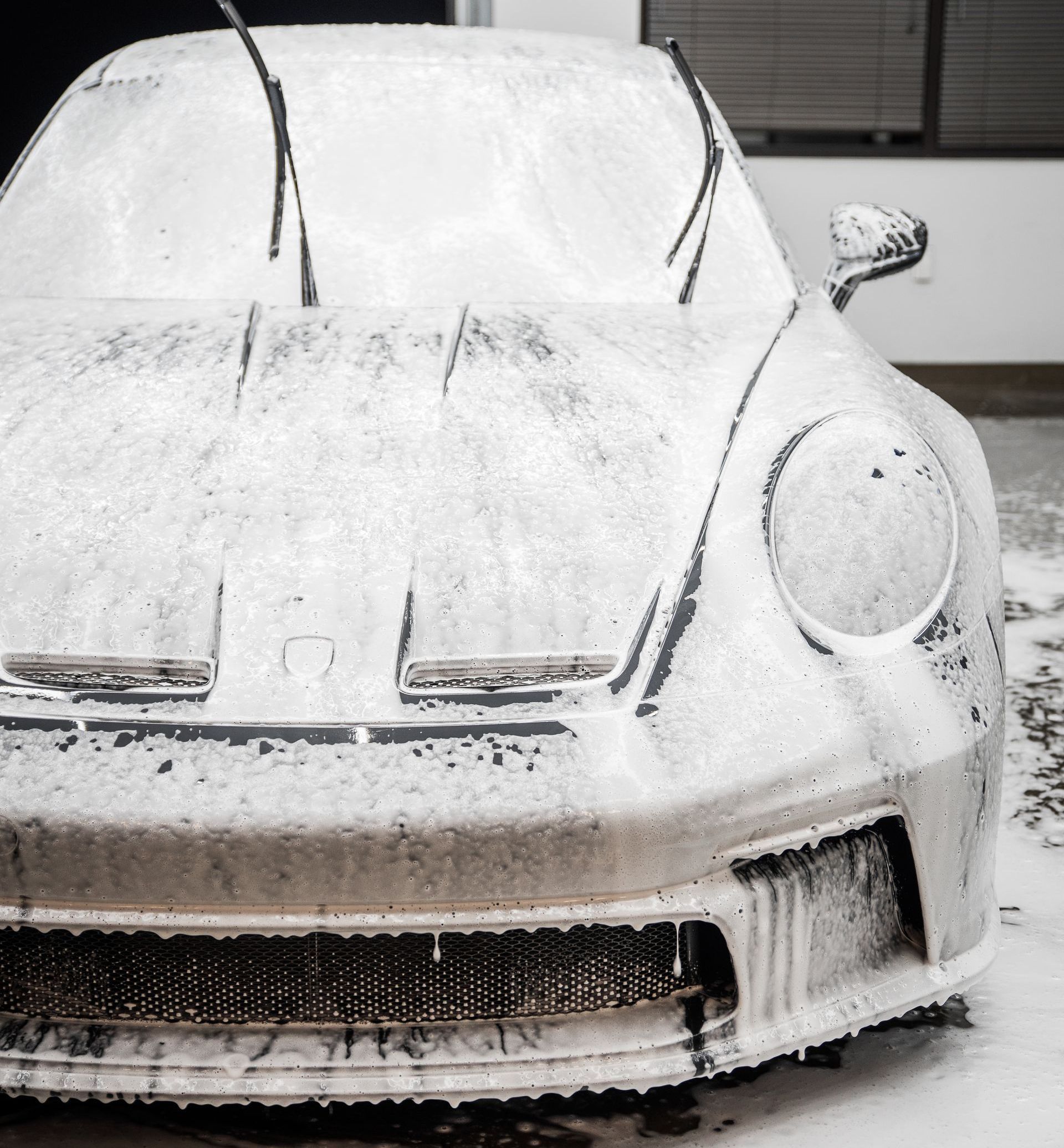 A man is washing a car in a garage.