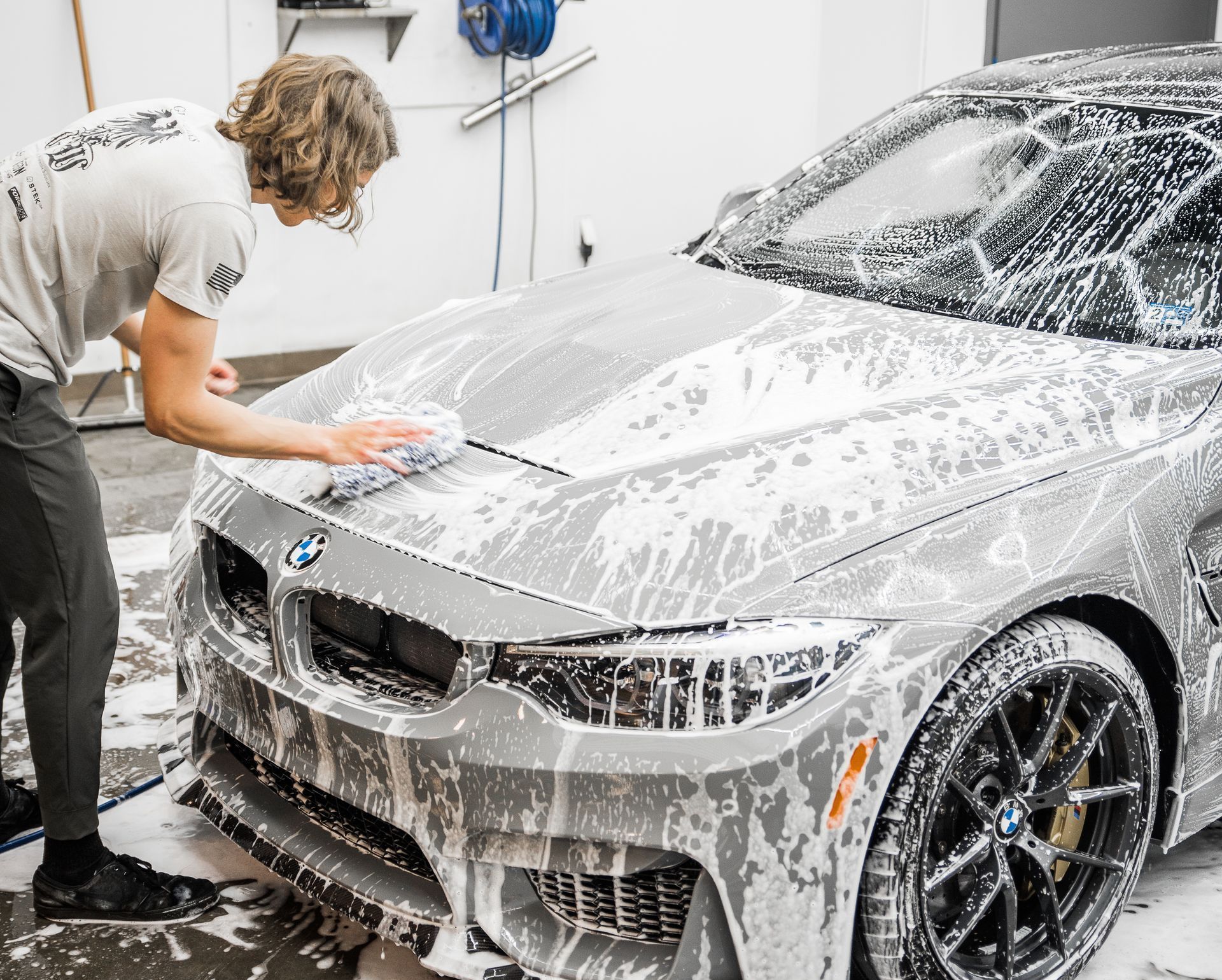 A man is washing a bmw m4 with foam.