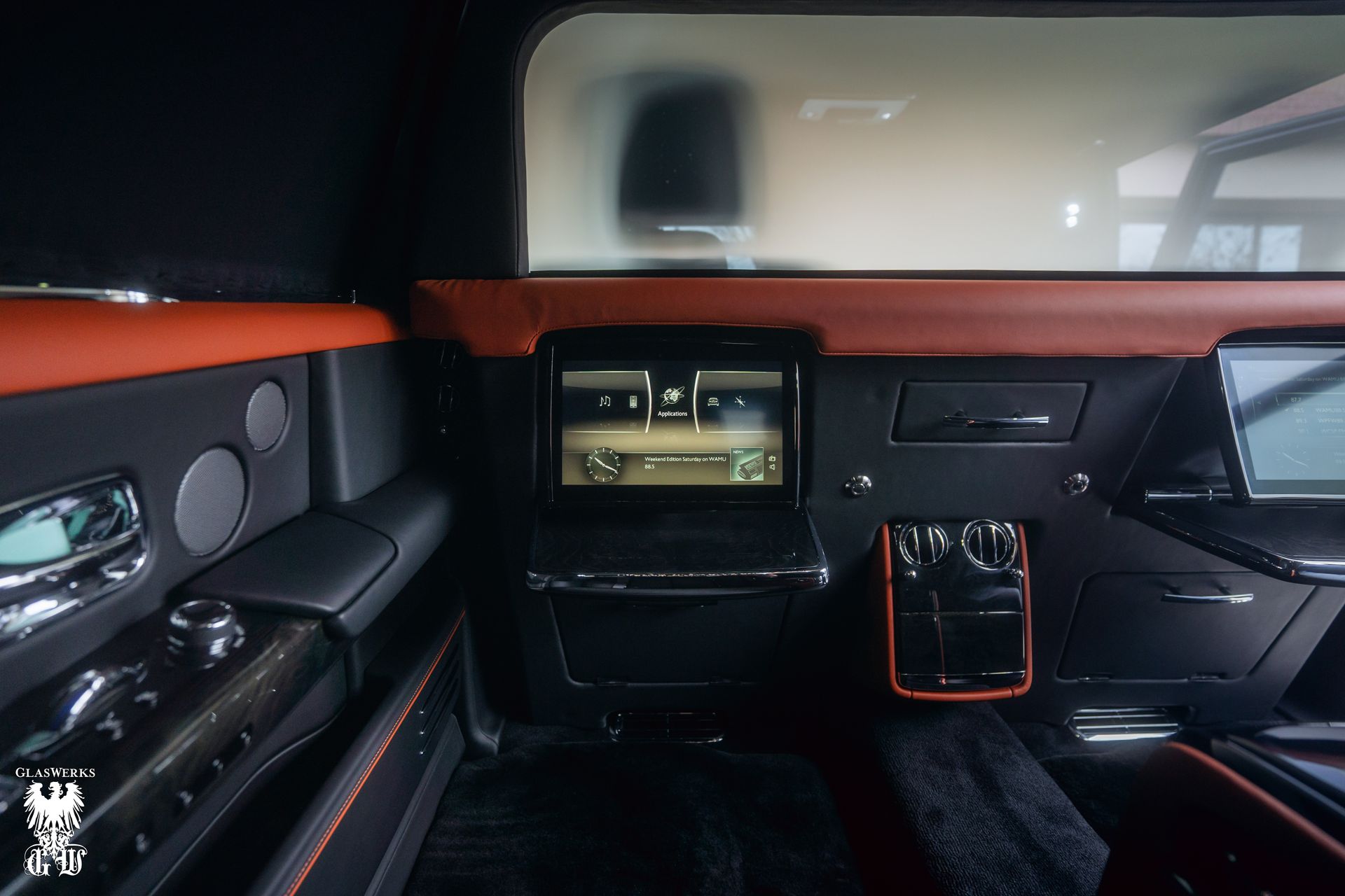 The interior of a rolls royce phantom limousine with a flat screen tv.