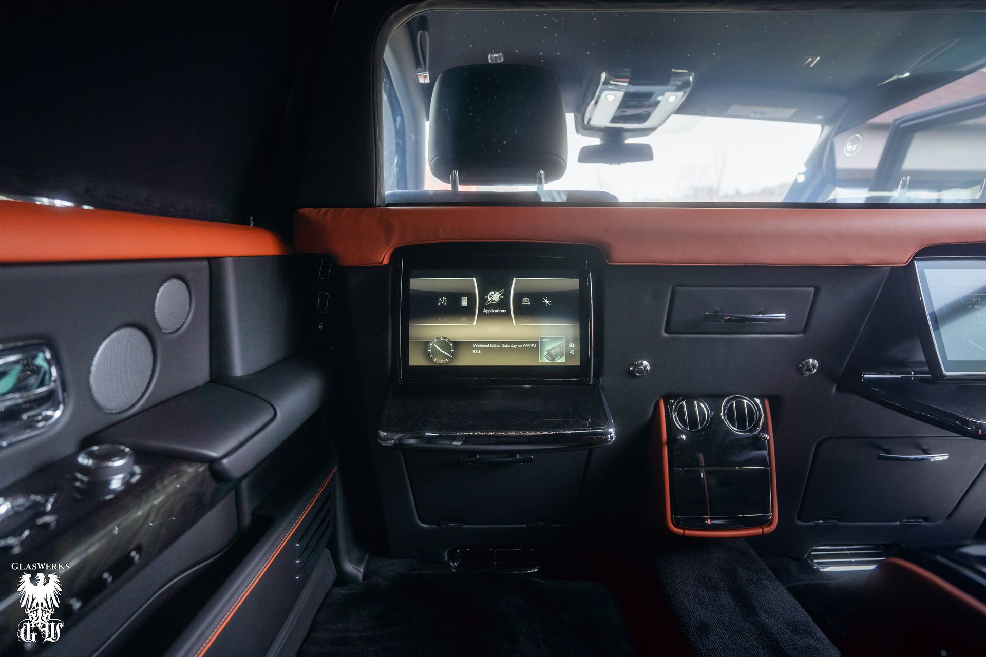 The interior of a rolls royce limousine with a flat screen tv.