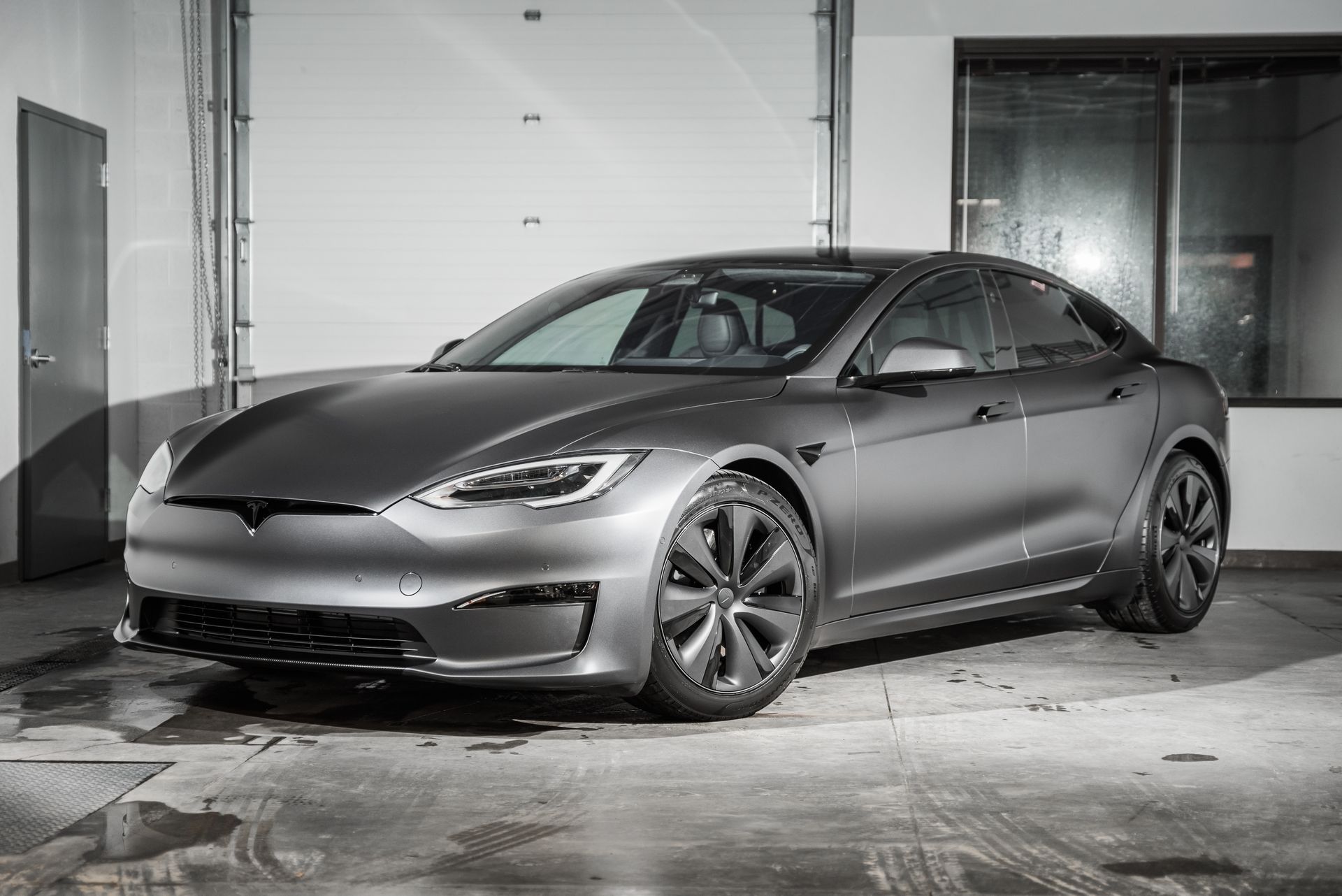 A tesla model s is parked in a garage next to a garage door.
