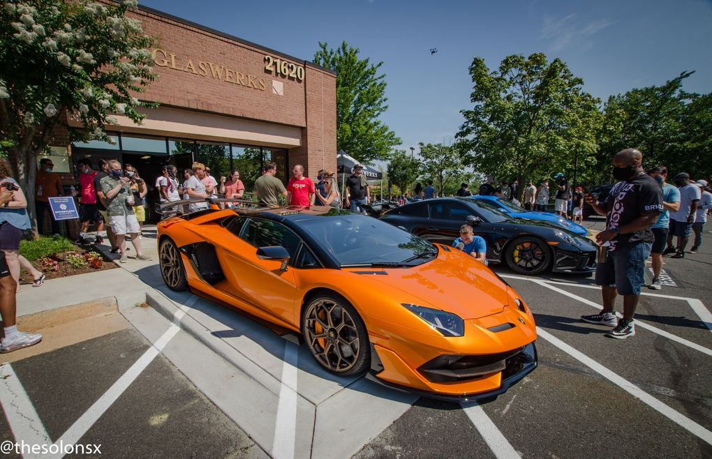 An orange lamborghini aventador is parked in a parking lot in front of a building.