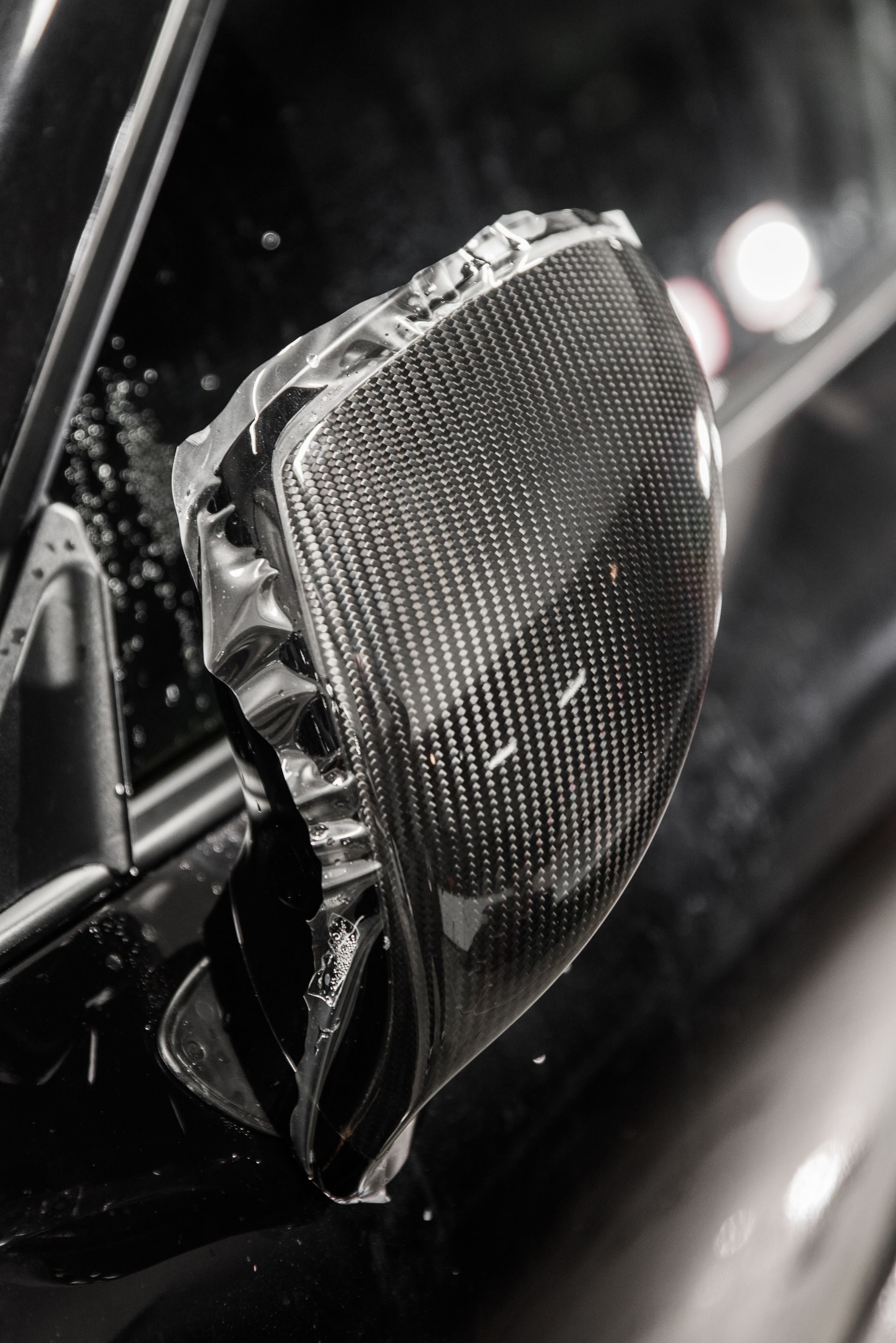 A close up of a car side mirror covered in plastic wrap.
