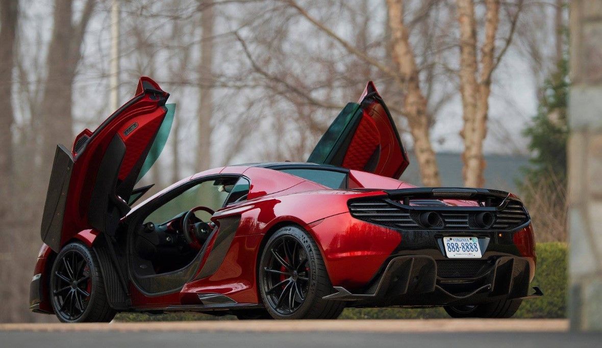 A red sports car with its doors open is parked on the side of the road.