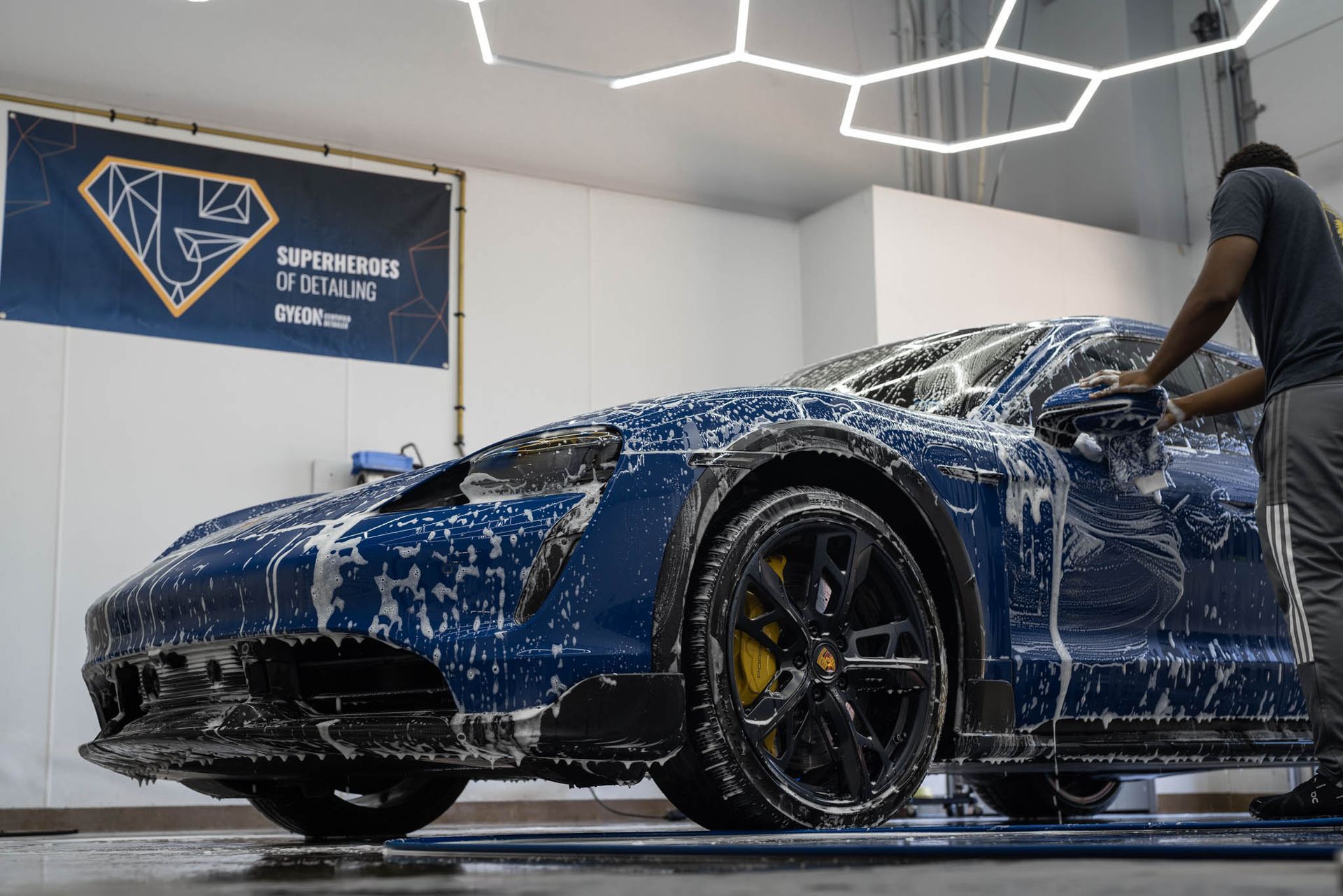 A man is washing a black car with soap and water.