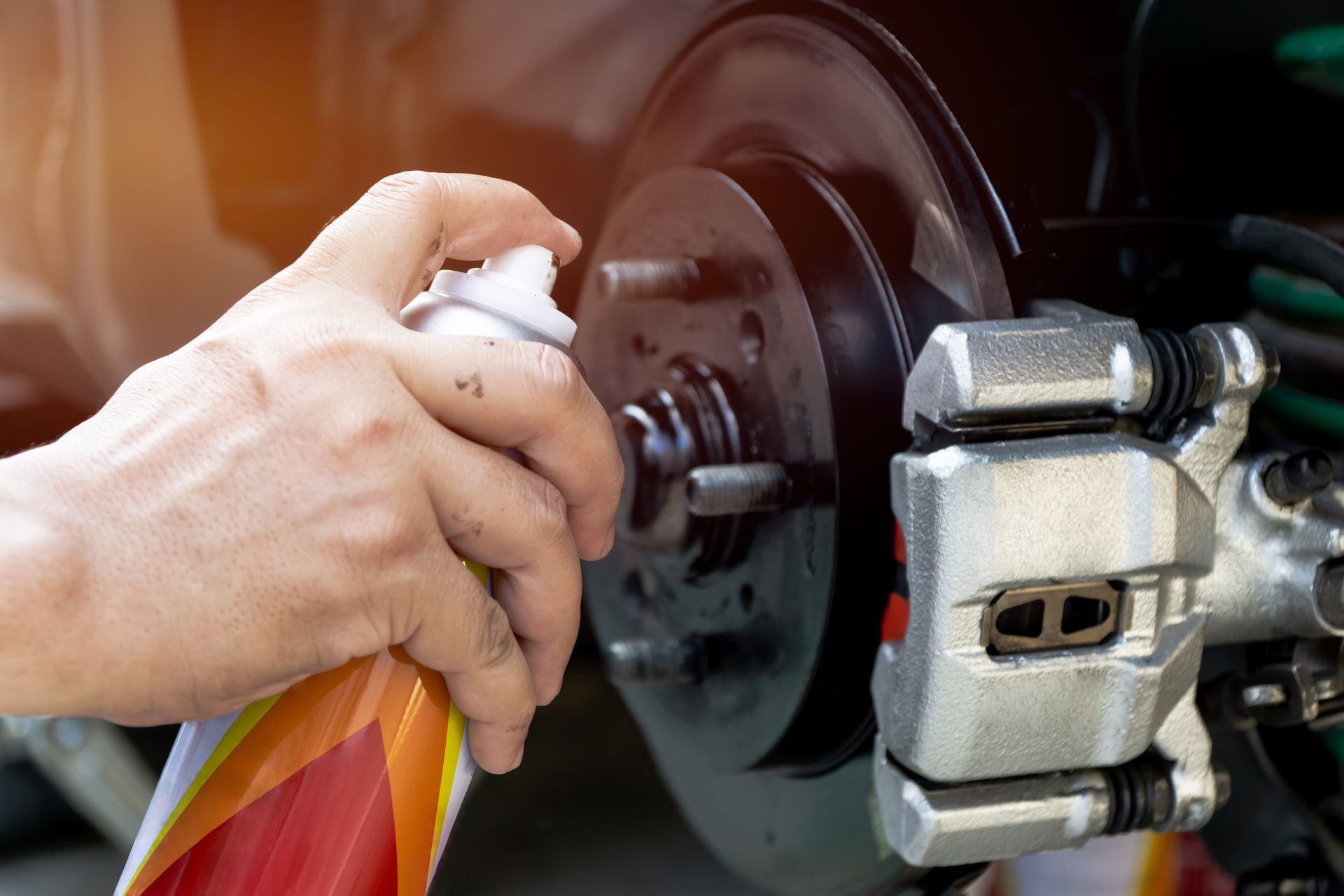 A person is spraying brake fluid on a car brake.