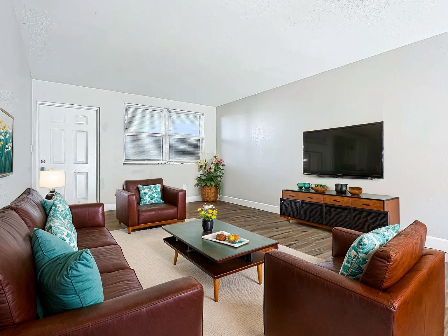 Living room with brown leather furniture, TV, and wooden coffee table.